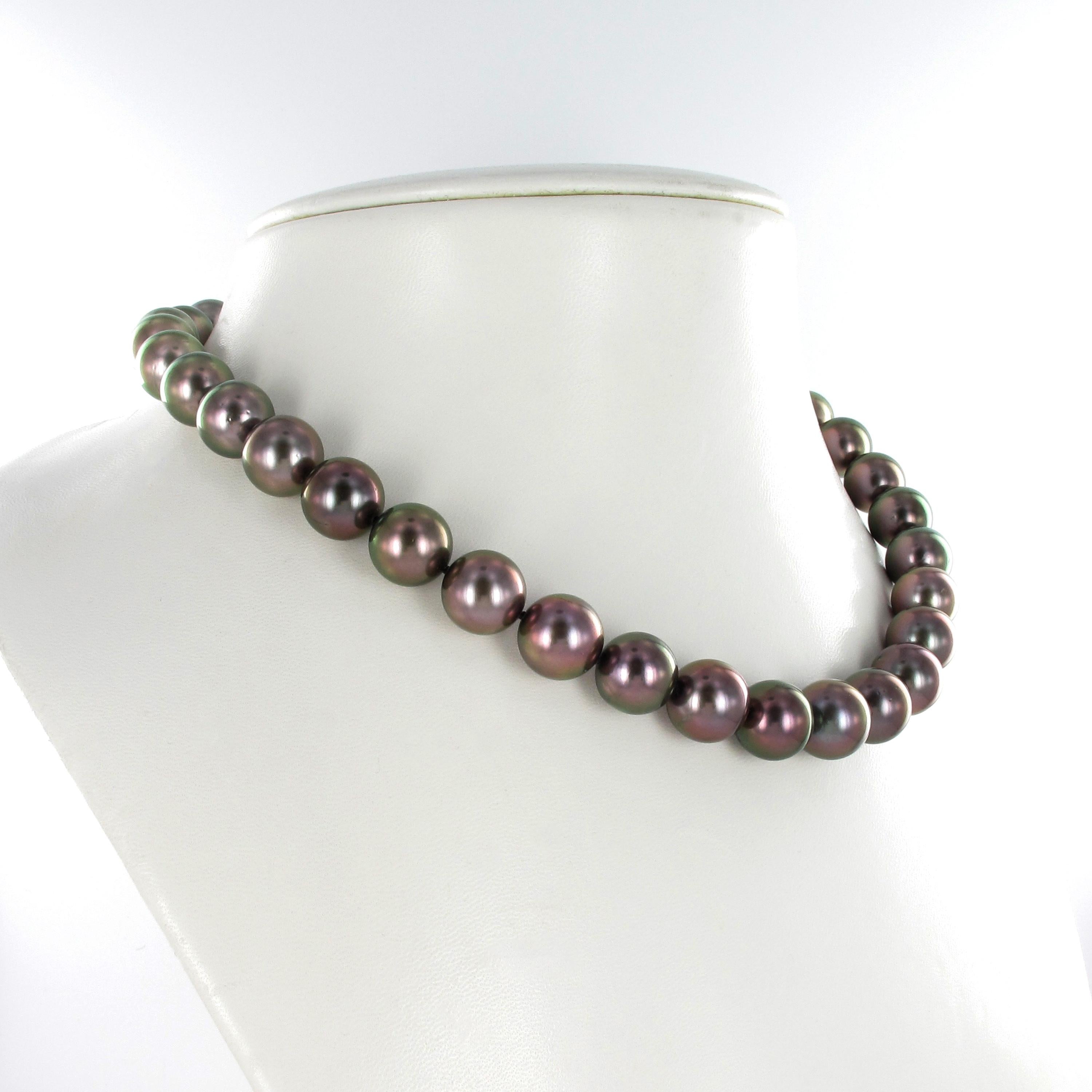 This strand consists of 35 round Tahitian cultured pearls graduating from 11.3 mm to 11.9 mm. Color range from soft gray to dark purple. Slightly spotted surface and with a very good luster. The ball clasp in 18 karat yellow gold is set with 12
