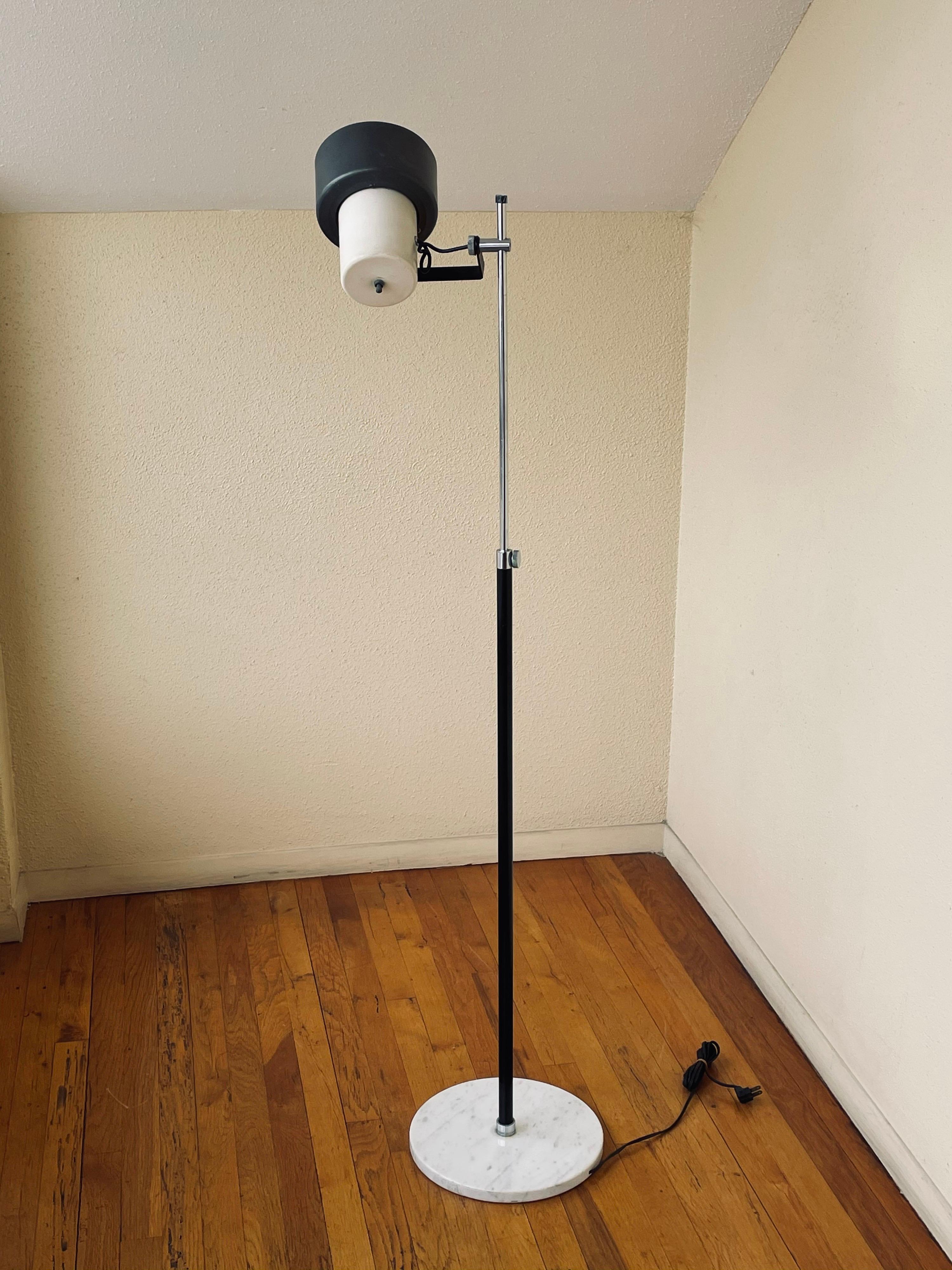 Simple modern circa 1970s multidirectional spot floor lamp by Arteluce, adjustable chrome post and swivel hade that rotates to any direction, sitting on solid marble round base. The lamp adjusts from 40