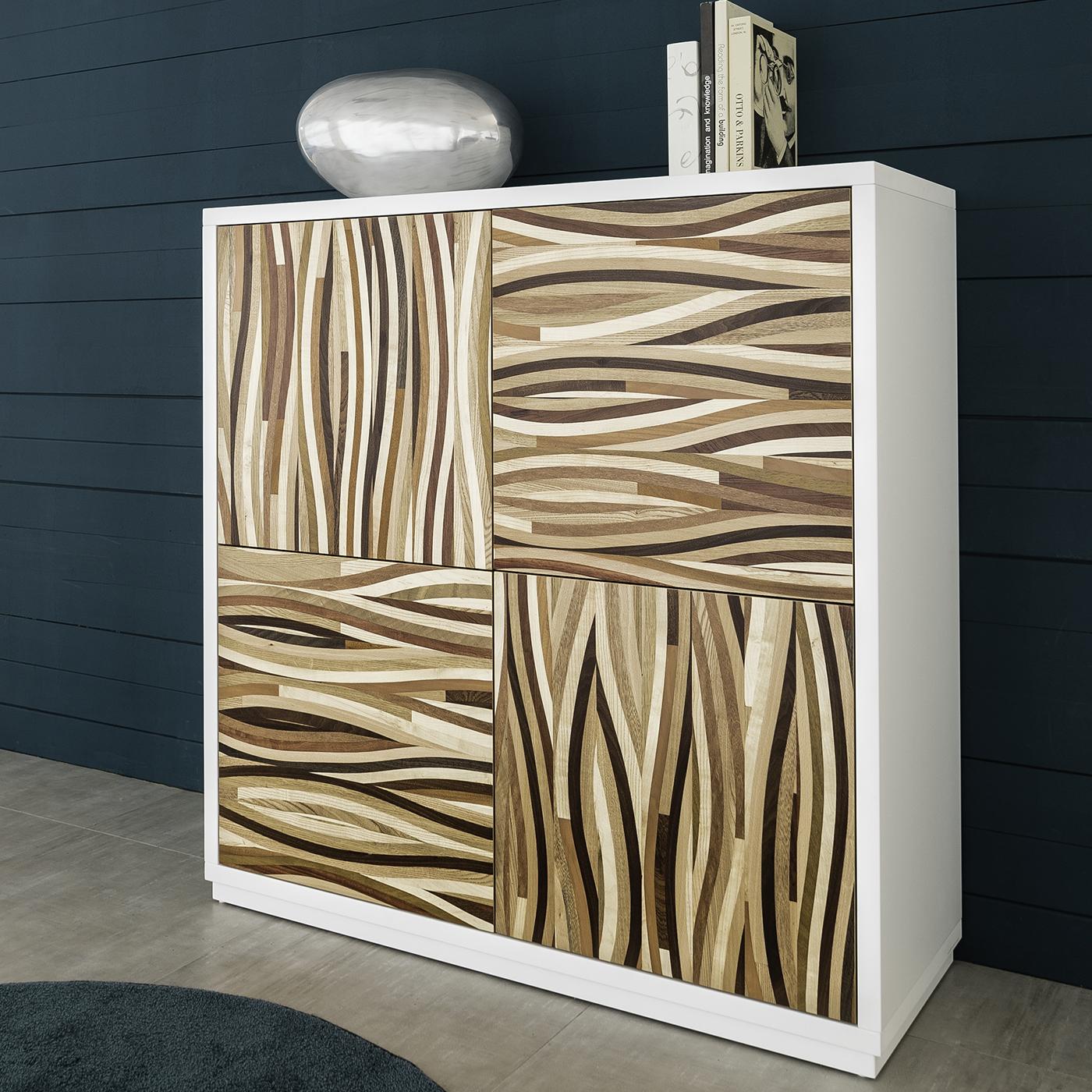This superb sideboard combines a linear silhouette with a striking decorative accent for a unique object of functional decor. Entirely crafted of wood, the structure is lacquered in glossy white, creating a clean frame for the four panels. These