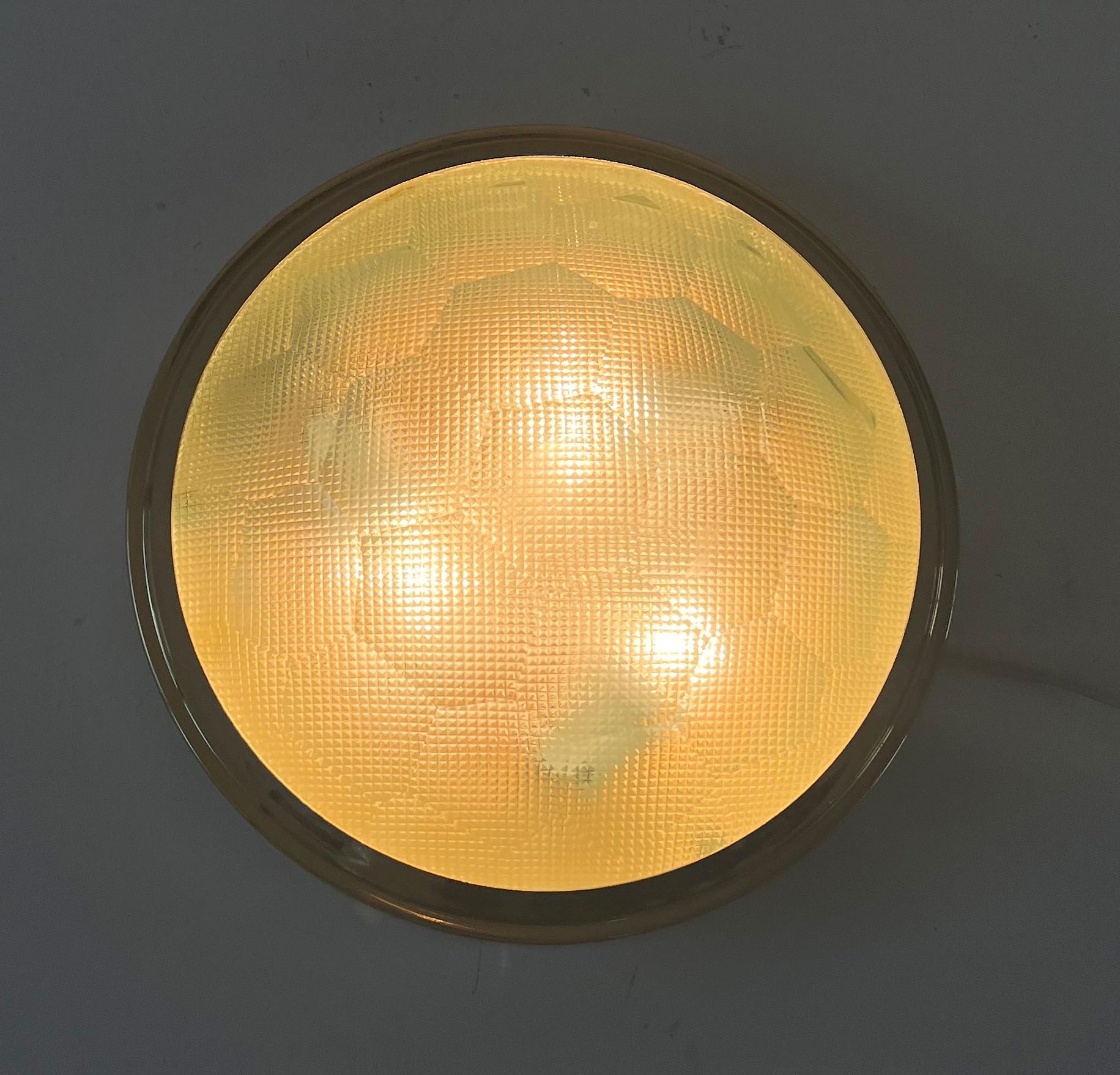 Space Age-Leuchte oder flush mount, hergestellt in Italien um 1960.
Die Leuchte besteht aus einem goldfarbenen Rahmen und 2 Kristallgläsern, von denen das äußere facettiert ist und das innere aus vierkantigem Pressglas besteht.
Beide Techniken sind