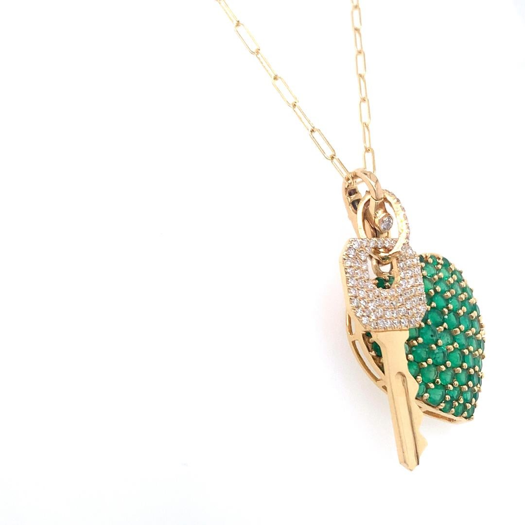 This is a gold necklace with two pendants. One of the key-shaped diamond pendants is formed completely of diamonds, and the other pendant is an emerald heart-shaped pendant. Both pendants are on an adjustable chain. The pendants, which are suspended