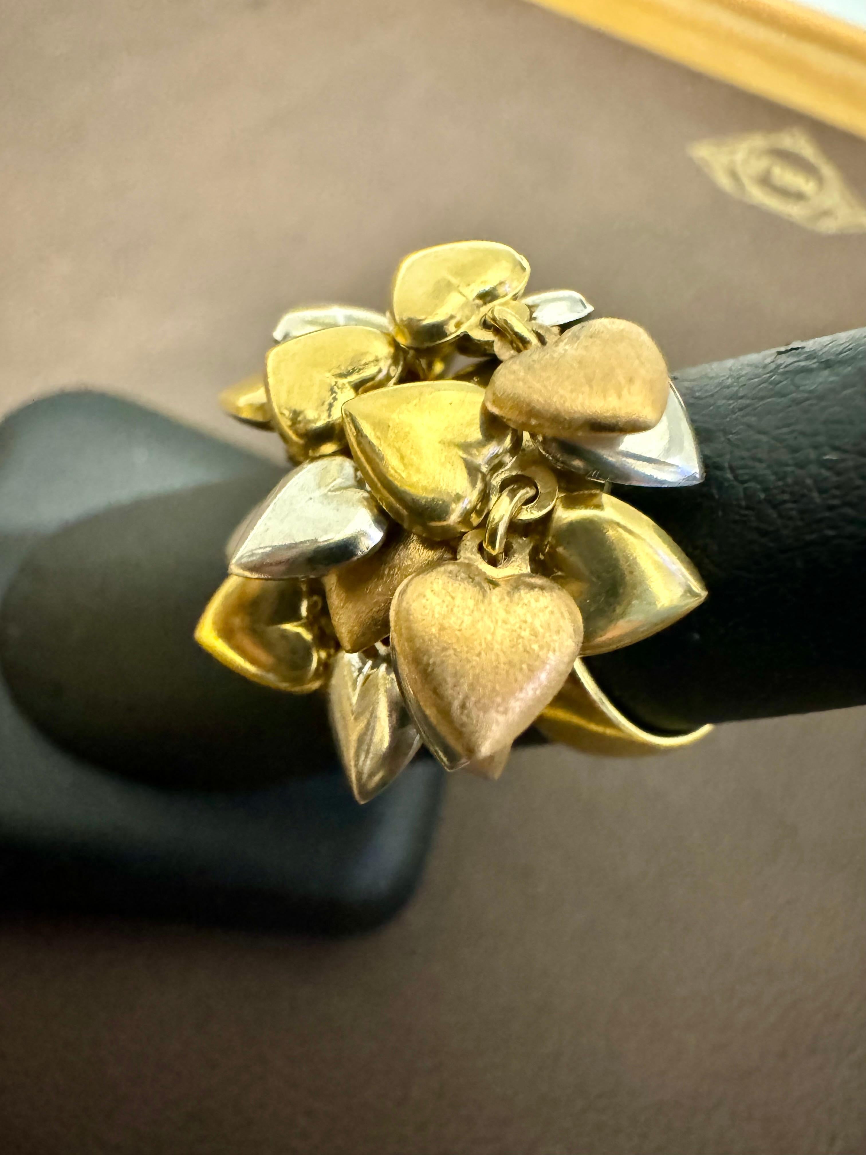Questo modello a 18 carati  L'anello d'oro presenta quasi 20 diversi charme a forma di cuore, I charms a forma di cuore in oro giallo, rosa e bianco sono  raggruppati su una fascia. Questo anello vintage è un bellissimo gioiello che vanta un colore