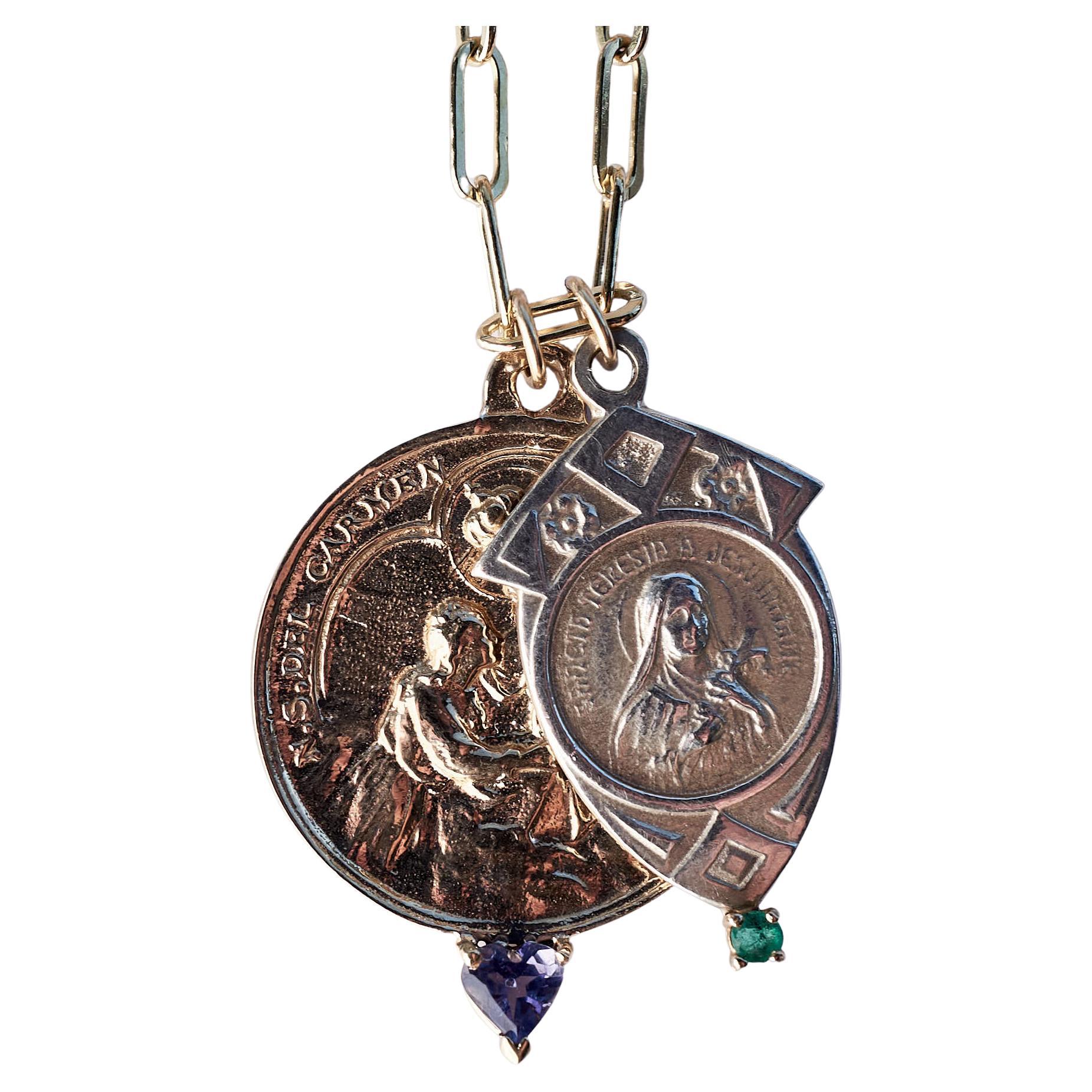 Este Collar Doble Medalla con dos Medallas de la Virgen María cuelga de una Cadena Rellena de Oro. Una de las medallas es redonda de bronce y tiene una Tanzanita Corazón engastada en oro, la otra Medalla es de plata de ley y tiene una Esmeralda