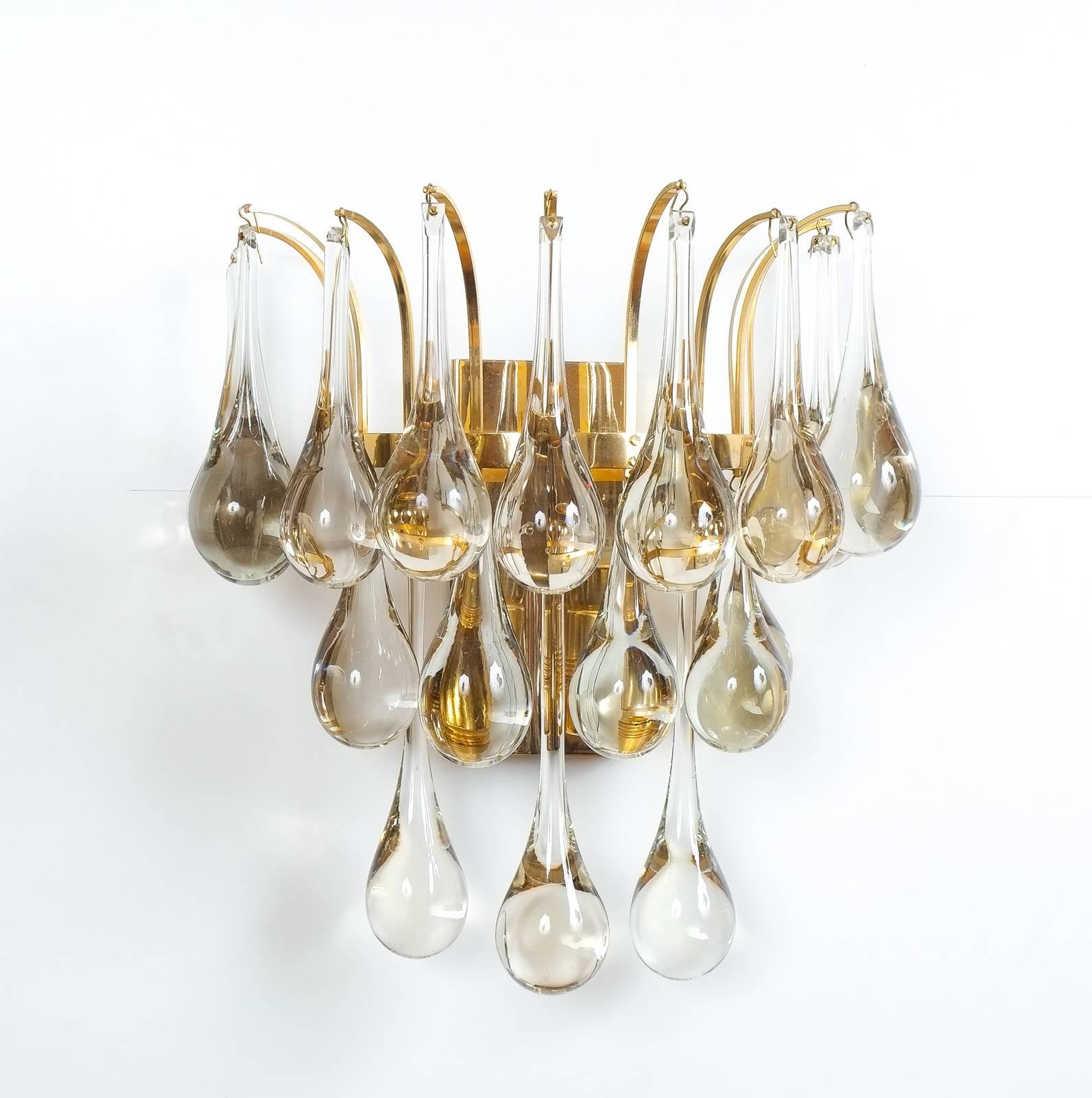Set of 4 wall lamps in brass with solid tear drop glass pieces- priced and sold per piece.

Beautiful multi-tiered set of four Murano glass tear drop sconces, 1960 composed of a multitude of hand blown smooth Murano glass drops hanging from a