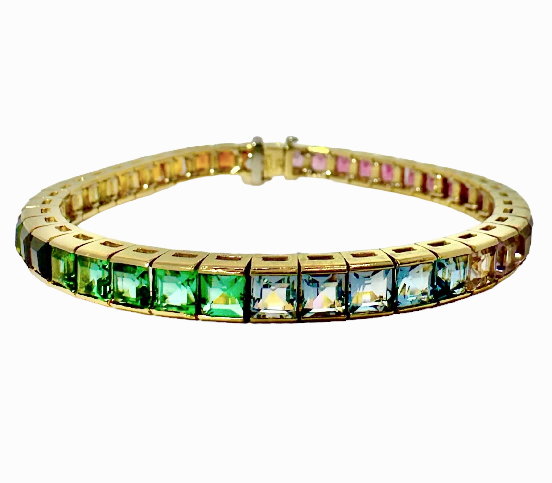 Magnifique bracelet en or jaune 18 carats serti d'un arc-en-ciel de pierres de différentes couleurs, dont certaines sont translucides et d'autres transparentes. Mesurant un quart de pouce de large, chaque maillon est conçu pour accueillir une pierre
