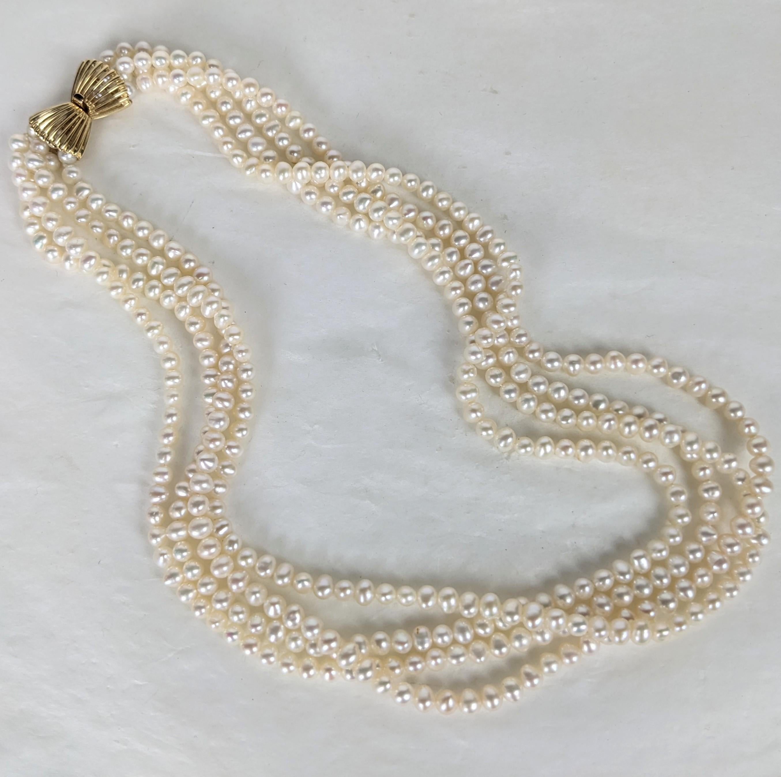 Classic Multistrand Cultured Pearl Necklace with 14k pierced gold clasp from the 1960's. 4 strands of well matched 5 mm cultured pearls can be worn draped or twisted as well. Elegant pierced 14k gold bow form clasp can be worn hidden or on side as