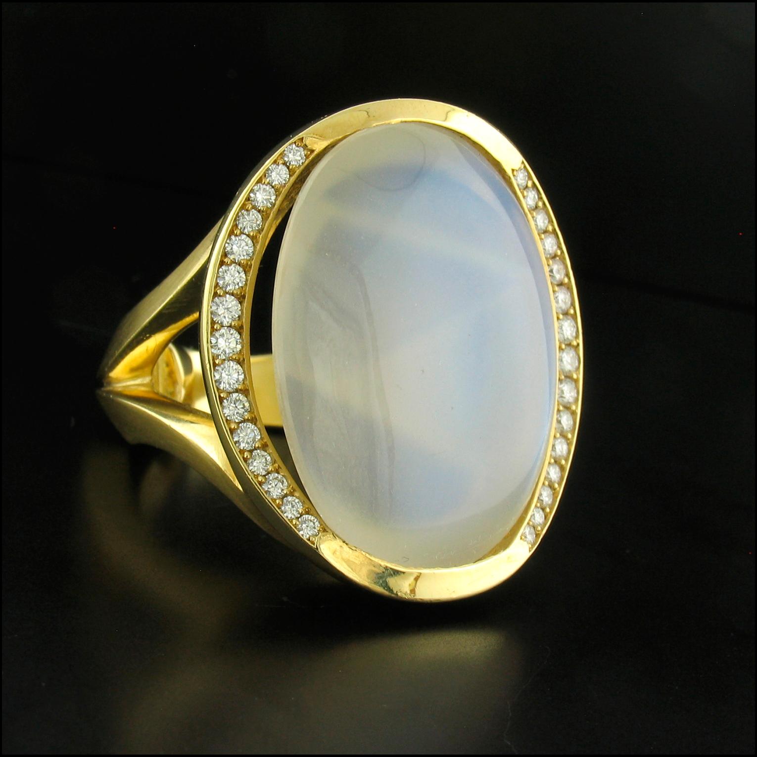 This ring was designed by Susan Helmich and features a spectacular, irreplaceable, glowing, oval-shaped, Munsteiner cut Blue Moonstone weighing 27.12 carats.  A very difficult color to capture in photos, one can see the cut and color more clearly on