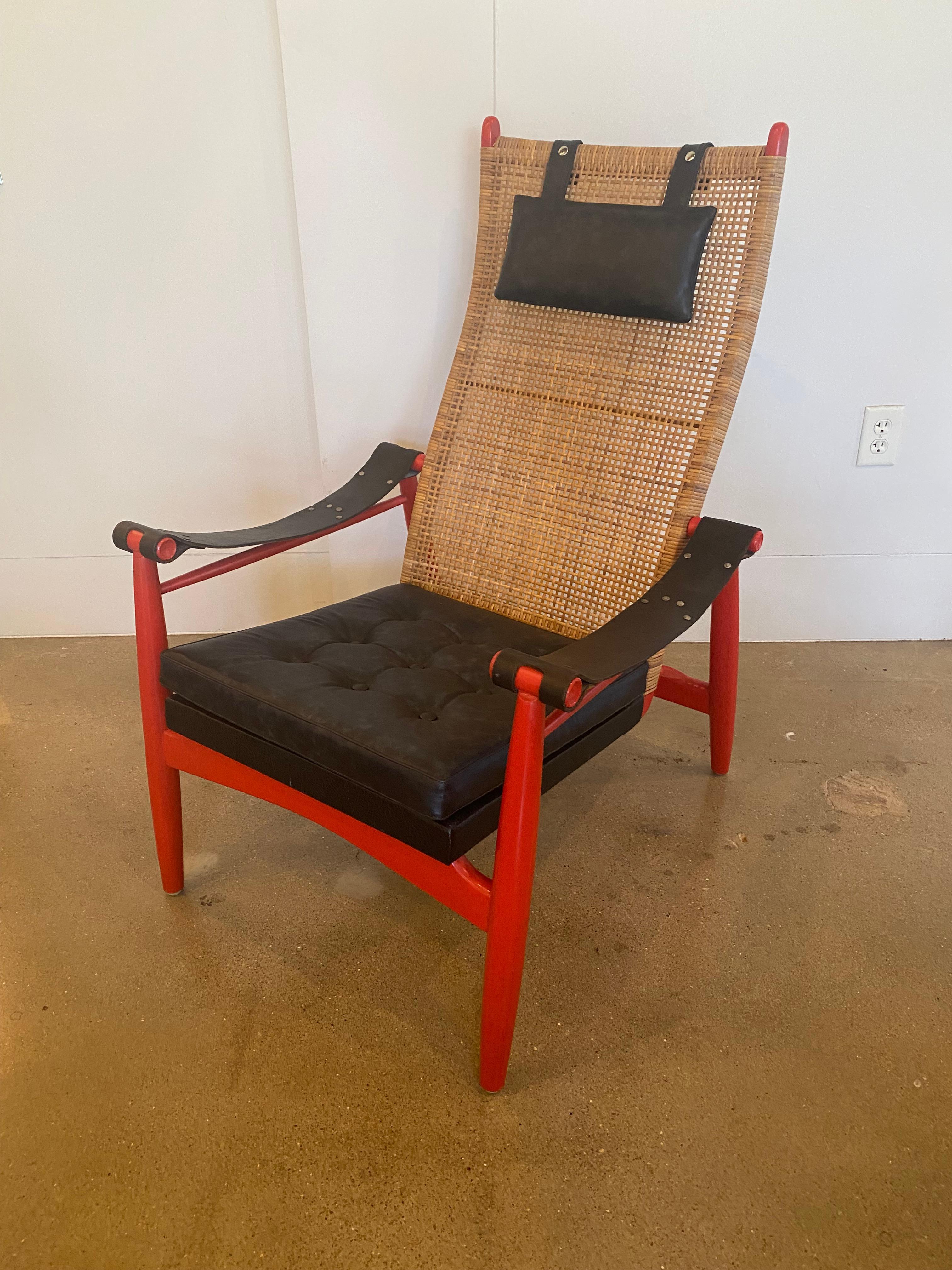 Mid-Century Modern cane backed armchair by P.J. Muntendam for Gebroeders Jonkers. Rarely found in the US and particularly unique because of the original red lacquer frame and the aniline dyed leather (charcoal to black in color) seat cushion , head