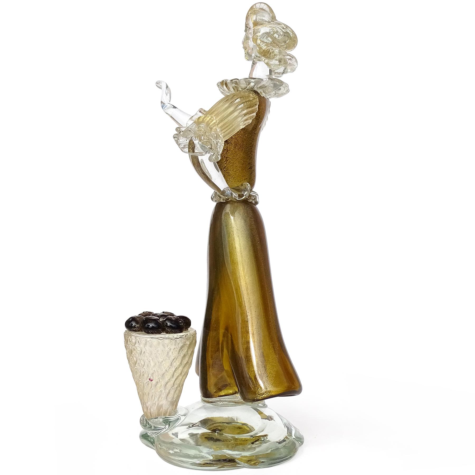 Beautiful and large, vintage Murano hand blown dark transparent amber / olive with gold flecks Italian art glass woman farmer / gardener sculpture. The piece is attributed to designer, and Master glass artist Alfredo Barbini. The woman figure has a