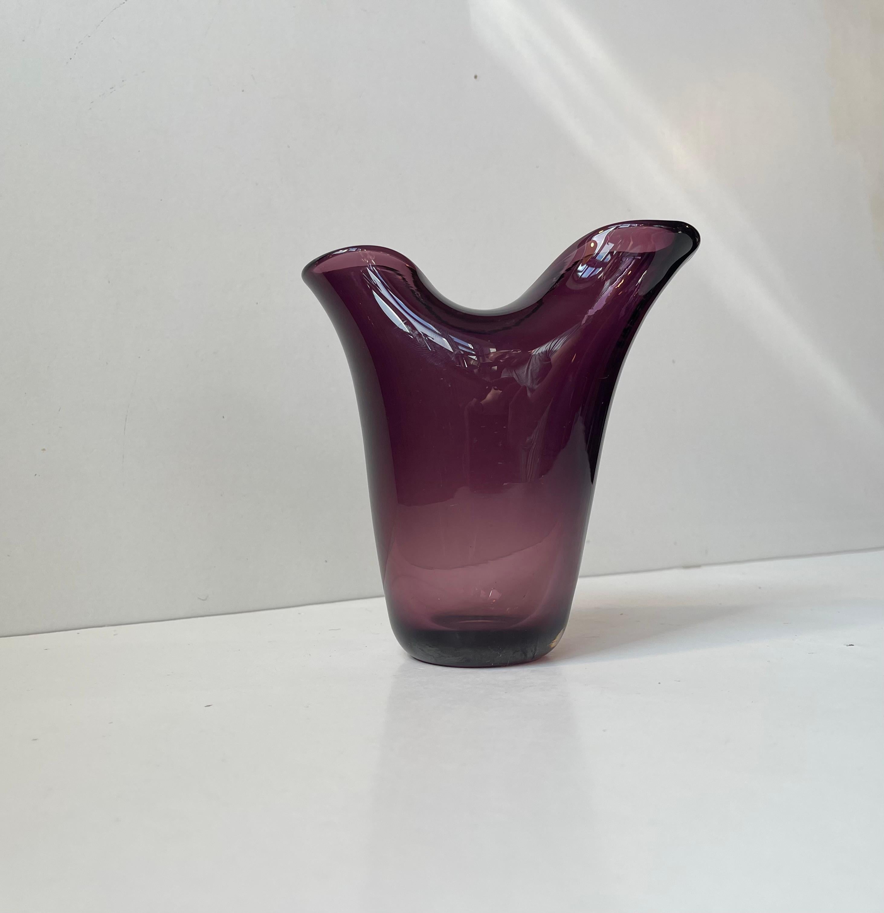 Un elegante vaso a forma libera a due falde in vetro ametista. Dal punto di vista stilistico, questo vaso condivide importanti caratteristiche con alcuni pezzi di Fulvio Bianconi degli anni '50 di Venini. Profondità del colore, eleganza della forma