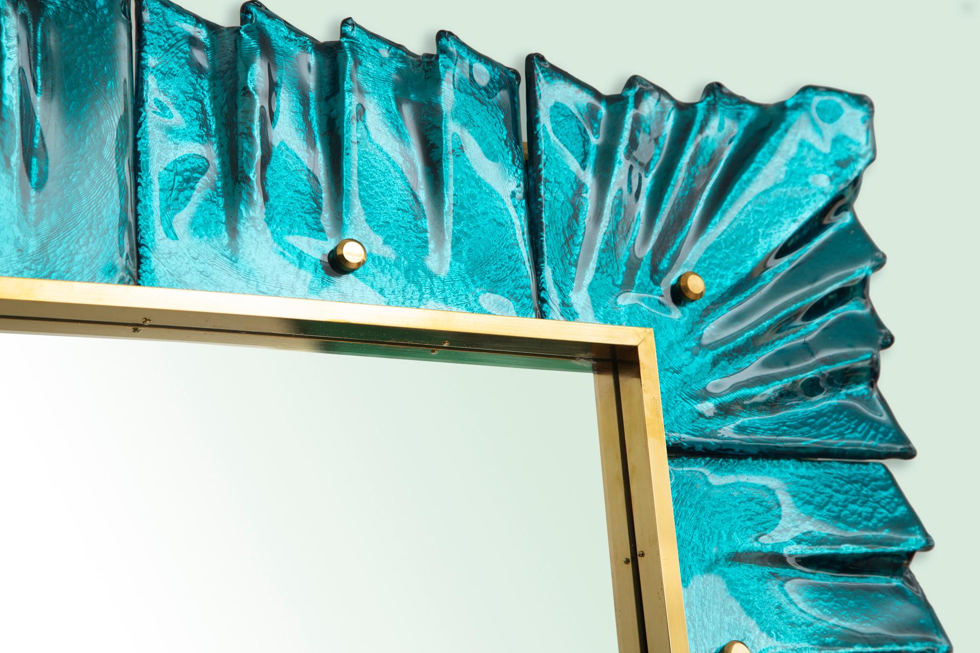 Contemporary Murano aquamarine glass framed mirror, in stock
Rectangular mirror plate surrounded with undulating glass tiles in aqua marine color held by brass cabochons.
Brass surrounding gallery
Handcrafted by a team of artisans in Venice,