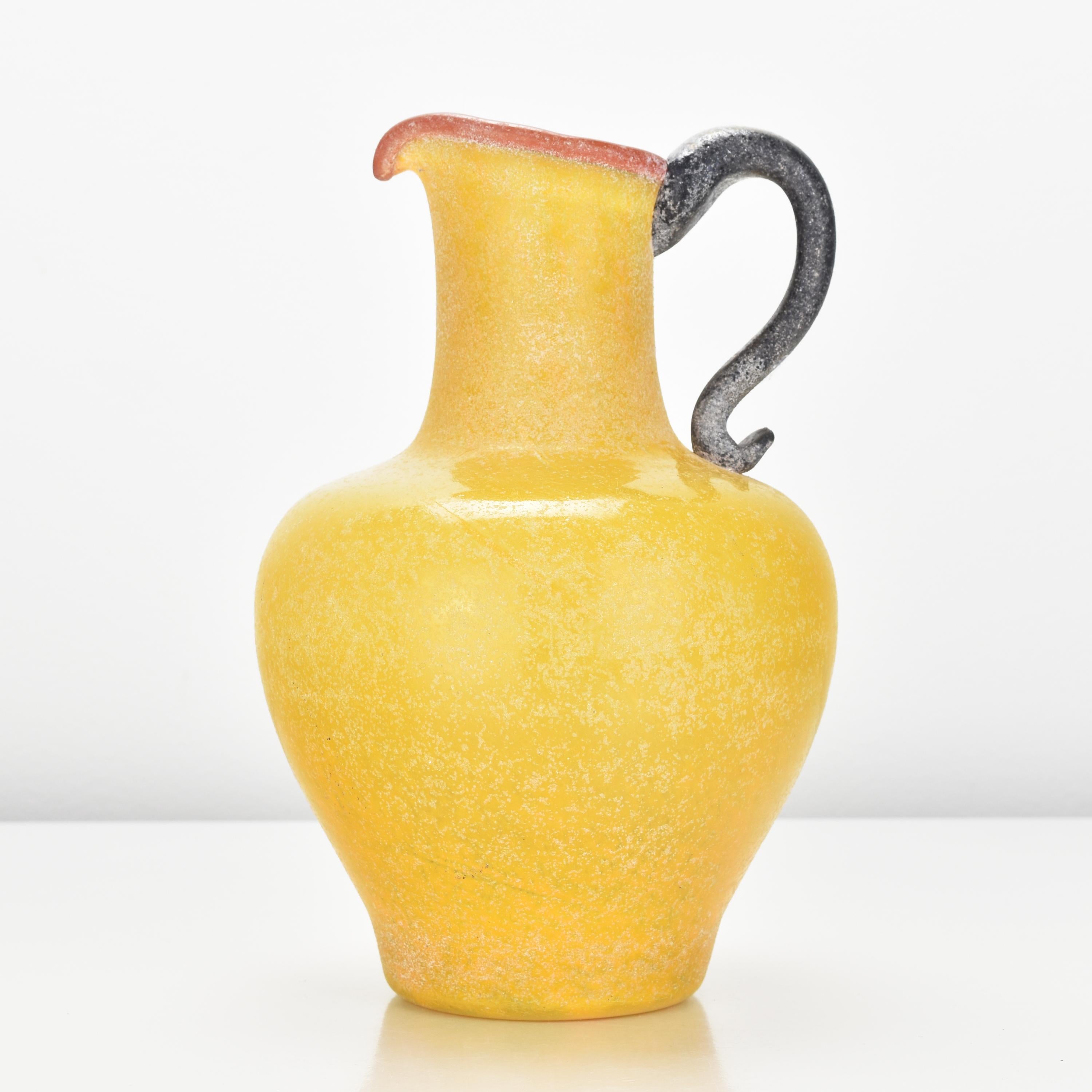 Vibrant yellow art glass jug vase with red upper rim and black handle probably made by Archimede Seguso.

Archimede Seguso (1909 - 1999) was a prominent and highly influential Italian glass artist and master glassblower from the island of Murano,