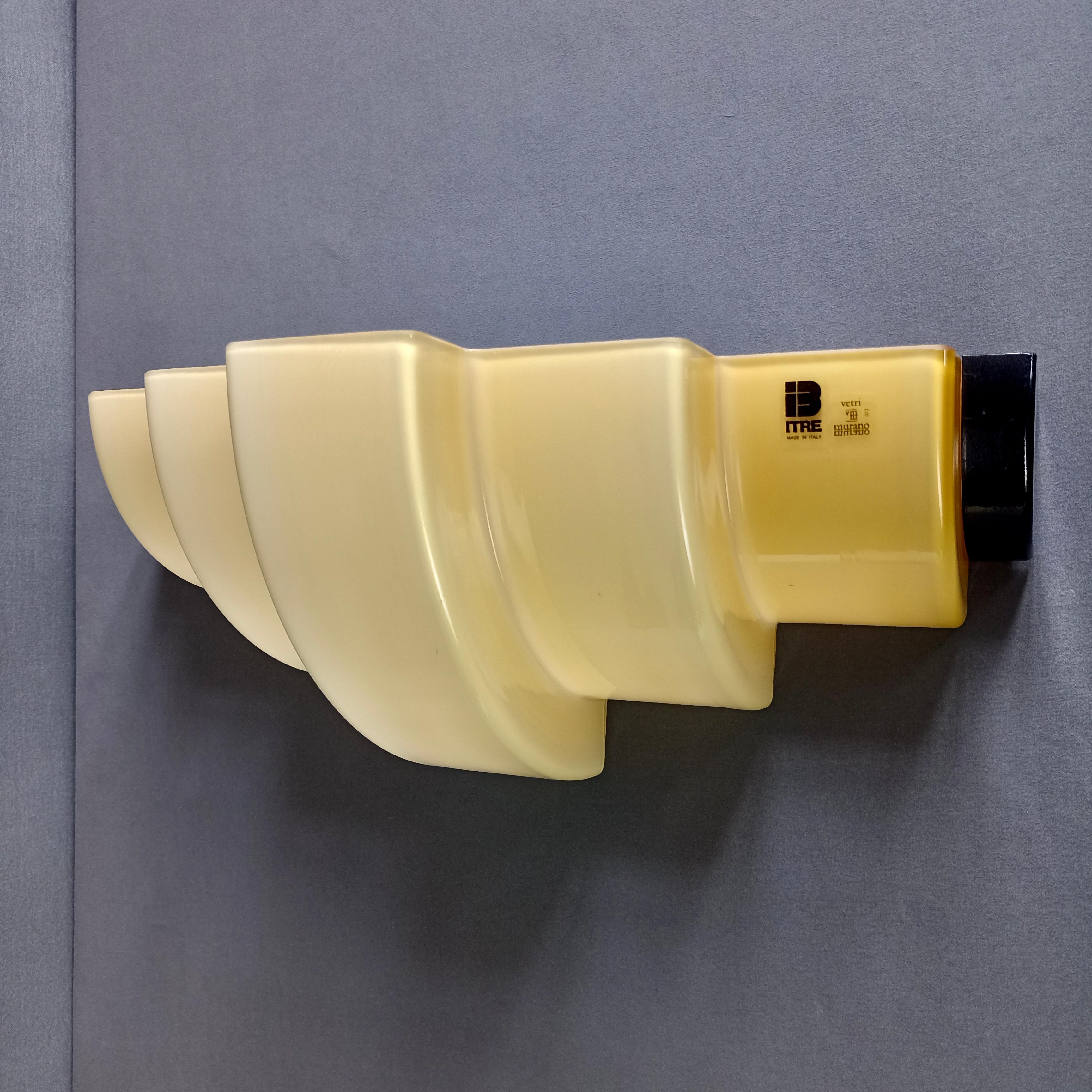Beautiful Murano ITre-marked 1990s two-light single wall lamp in cased white and warm yellow glass. 
The shape of the glass lampshade has been modeled in a very special way, creating three different levels from the center towards the edges, harking
