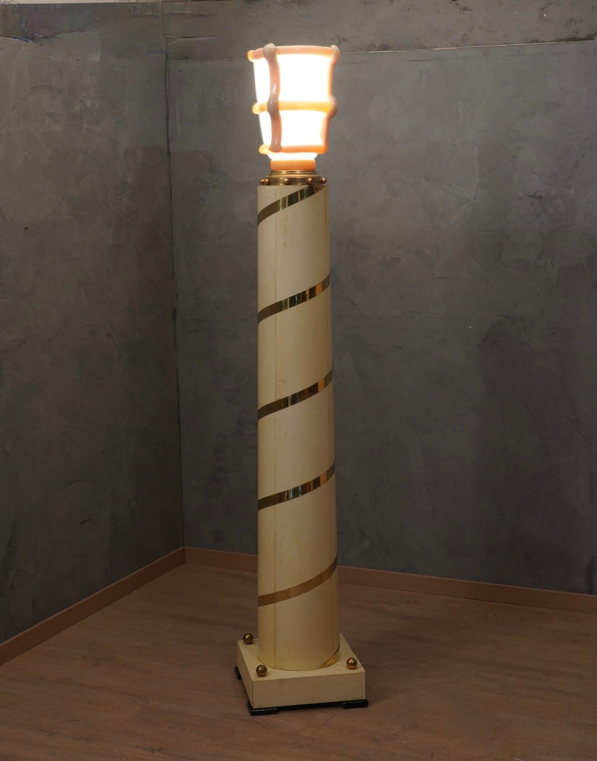 Splendid and regal floor lamp with a perfect combination of precious materials such as Murano glass, brass and goatskin.

The column with a cylindrical but slightly conical structure is made of wood and is completely covered in goatskin; a brass