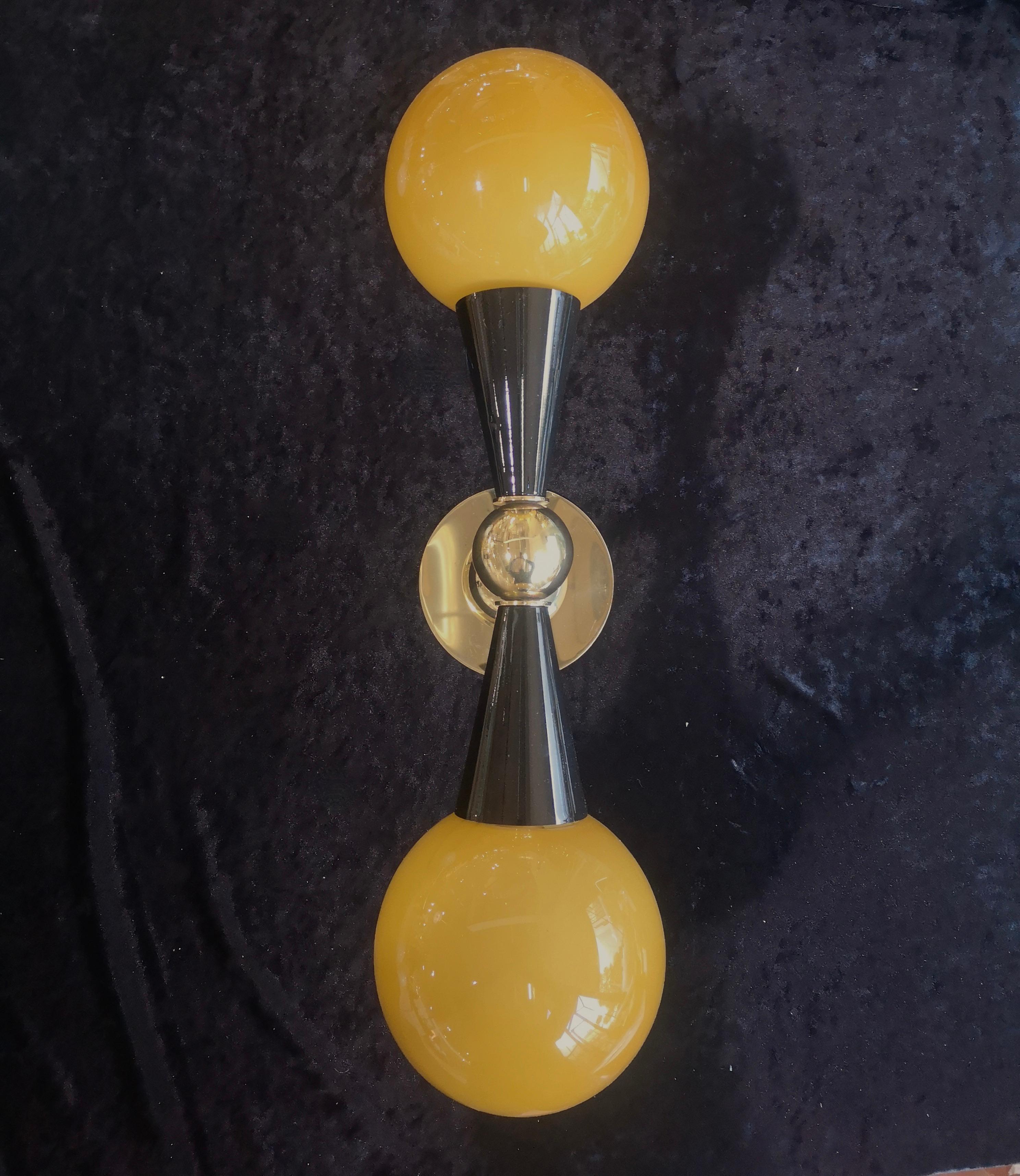 Refined and delicate design for this wall light with golden yellow Murano glass.

The applique are made up of a brass structure that allows the superimposed housing of two beautiful Murano glass spheres of a golden yellow color. The design is very