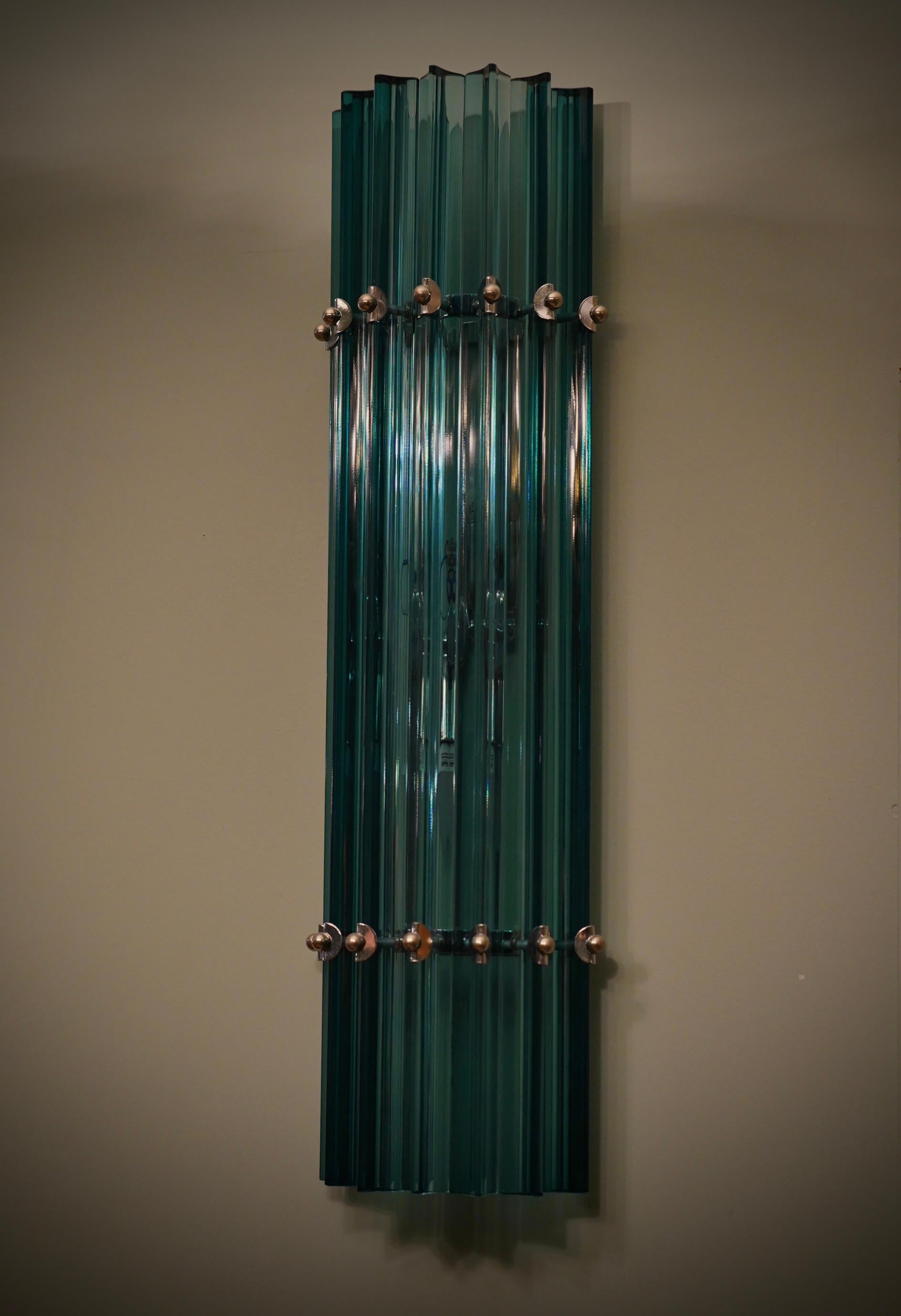 Fascinante color azul cobalto para este aplique de cristal de Murano, un diseño fascinante y muy alargado, con un bello acabado de estos triedros.

Todo en rico cristal de Murano. Tienen una estructura semicircular de metal cromado; alrededor se han