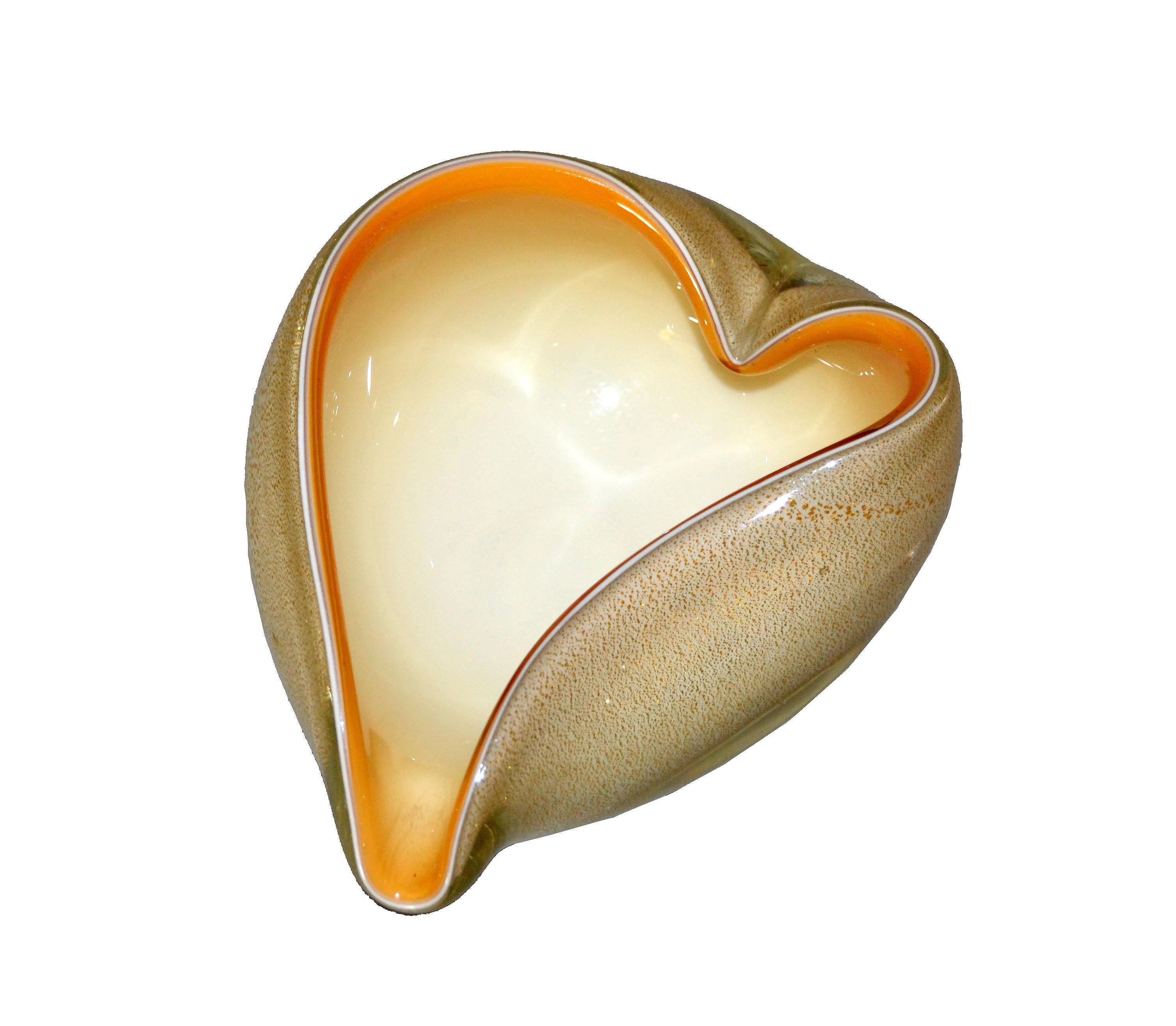 Hand blown heart shaped beige & caramel colored Murano art glass ashtray, decorative catchall or bowl made in Italy and inspired by Alfredo Barbini.
Beige filled glass decorated with intricate gold leaf patterns and encased with clear Murano