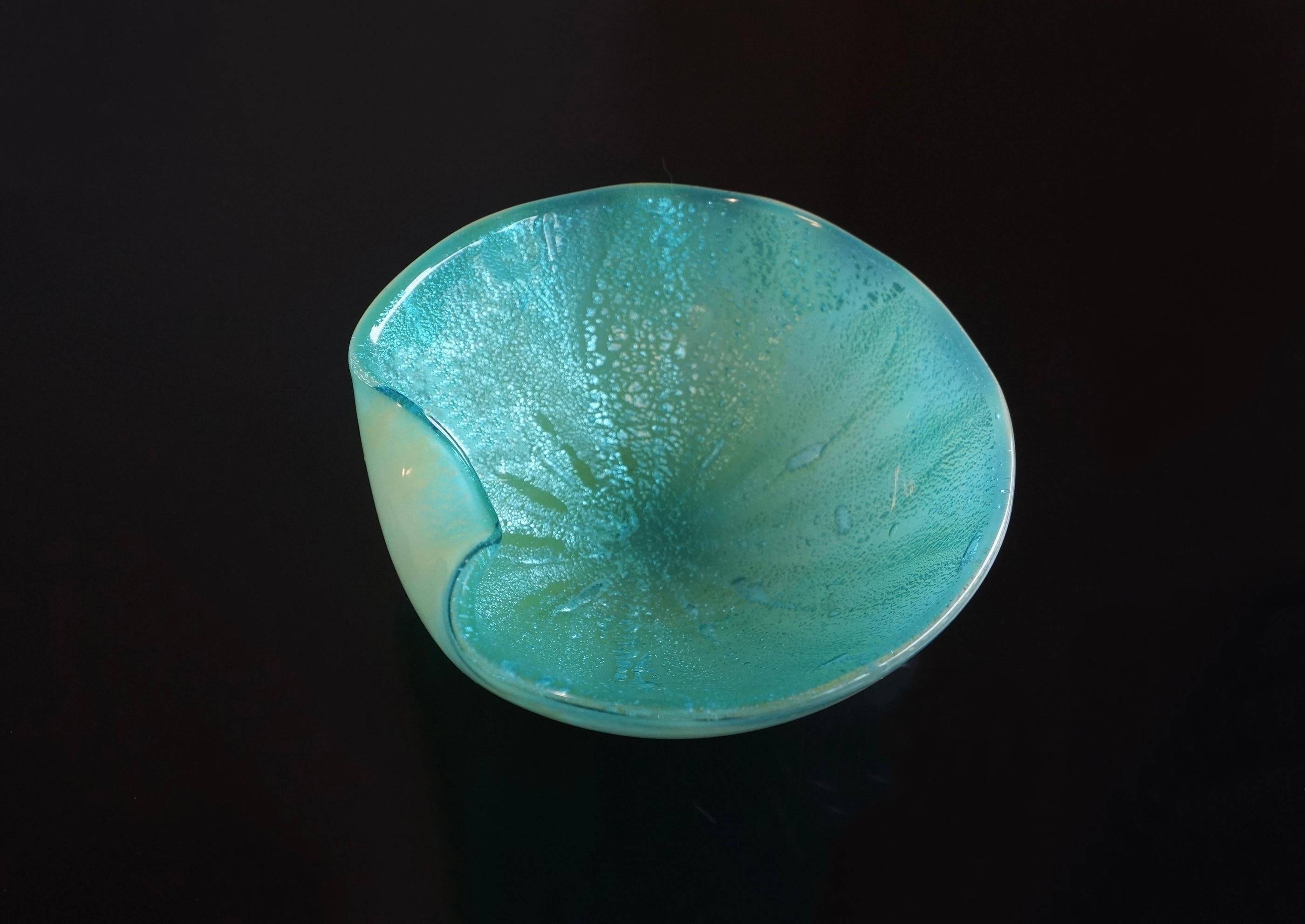 Spectaculaire plat décoratif en verre d'art de Murano bleu et notes de vert aqua, attribué à Archimede Murano. Ce bol est fait de verre d'art bleu avec des mouchetures d'aventurine dans les tons bleus. L'extérieur est d'une couleur de verre bleu