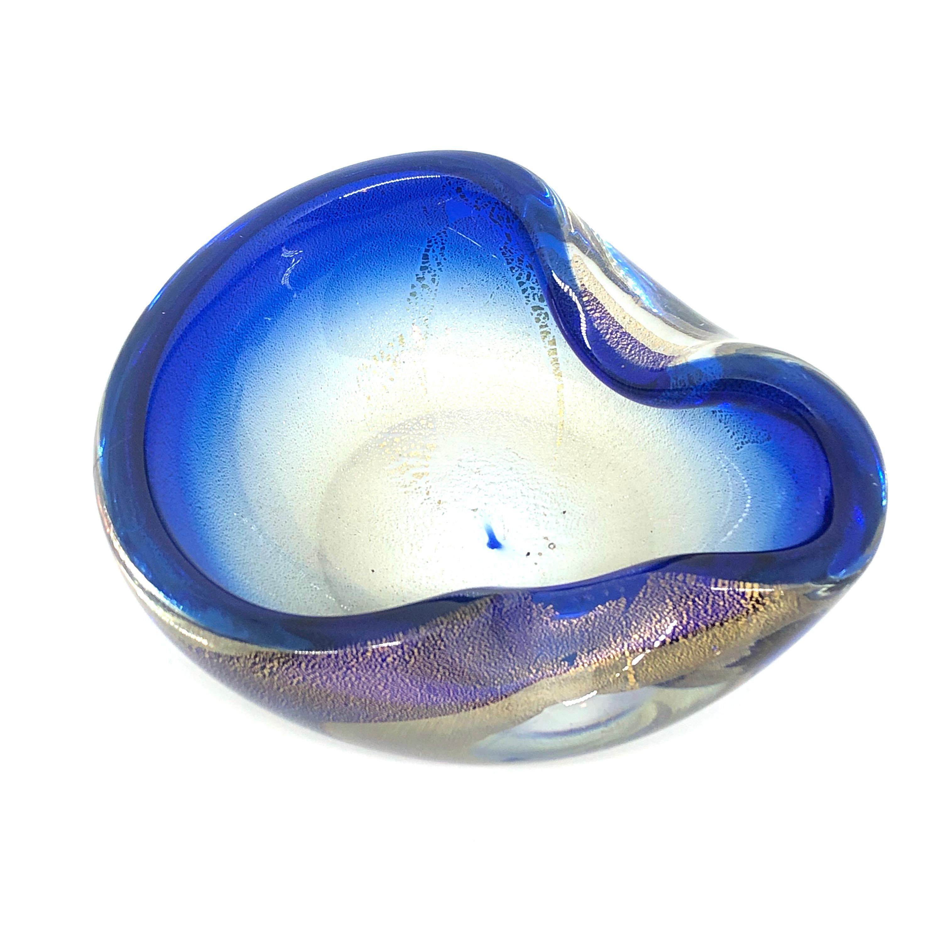 Gorgeous hand blown Murano art glass piece with Sommerso and bullicante techniques. A beautiful organic shaped bowl, catchall or ashtray in clear glass with blue on the outside and golden glitter glass on the inside. Italy, 1970s.