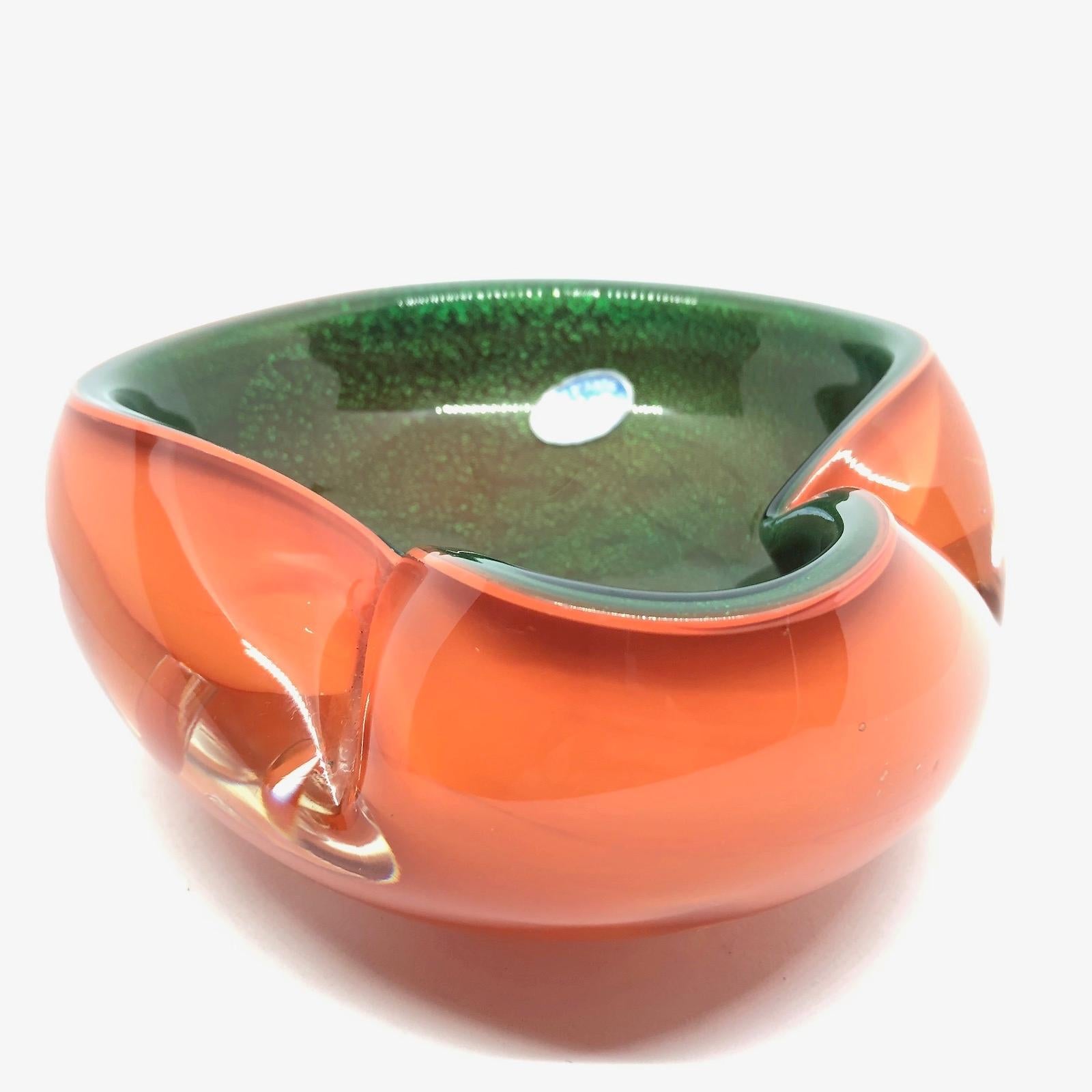 Gorgeous handblown Murano art glass piece with Sommerso and bullicante techniques. A beautiful organic shaped bowl, catchall or ashtray in clear glass with orange on the outside and green glitter glass on the inside. Italy, 1970s.