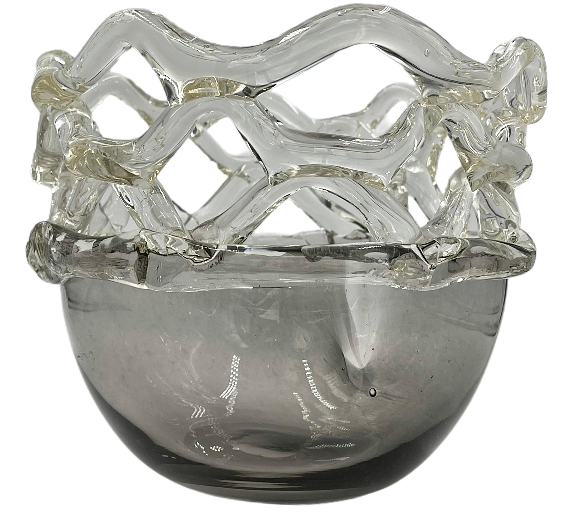Handgeblasene Kunstglasschale mit geschnürtem Deckel. Kunstvoll und aufwendig im Design. Klare Spitze mit einem rauchigen Glasgefäß. Perfekter Vintage-Zustand.

Maße: 7.5