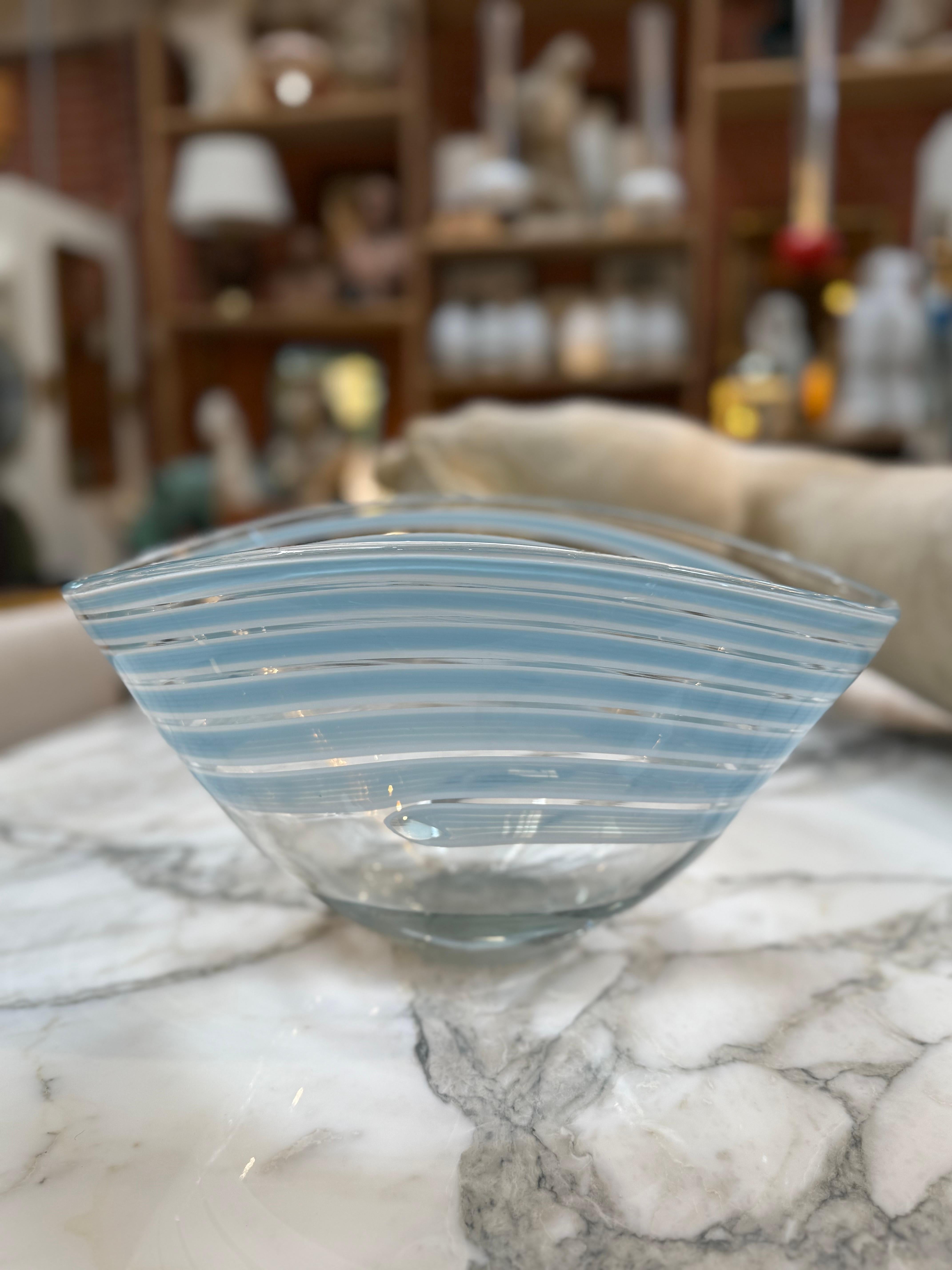 Élégante coupe en verre de Murano présentant une forme asymétrique gracieuse et un délicat motif rayé translucide bleu et transparent. Soufflée à la main par des artisans vénitiens, cette pièce met en valeur l'art fluide de l'artisanat de Murano. Sa