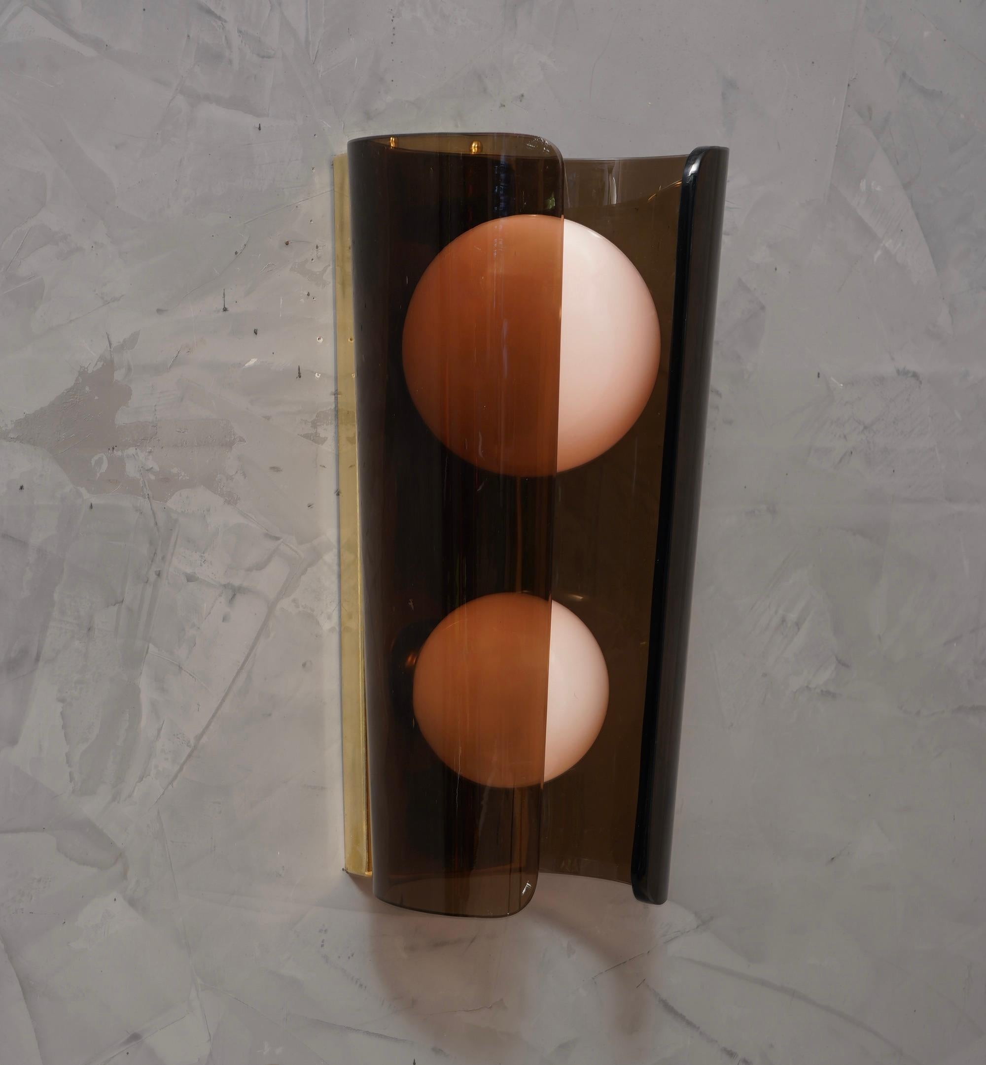 The rounded shape of the brown glass creates a very nice contrast with the two pale pink glass spheres, a unique and original design for this Murano wall light.

The applique is formed by a rectangular brass structure, to which a large and thick