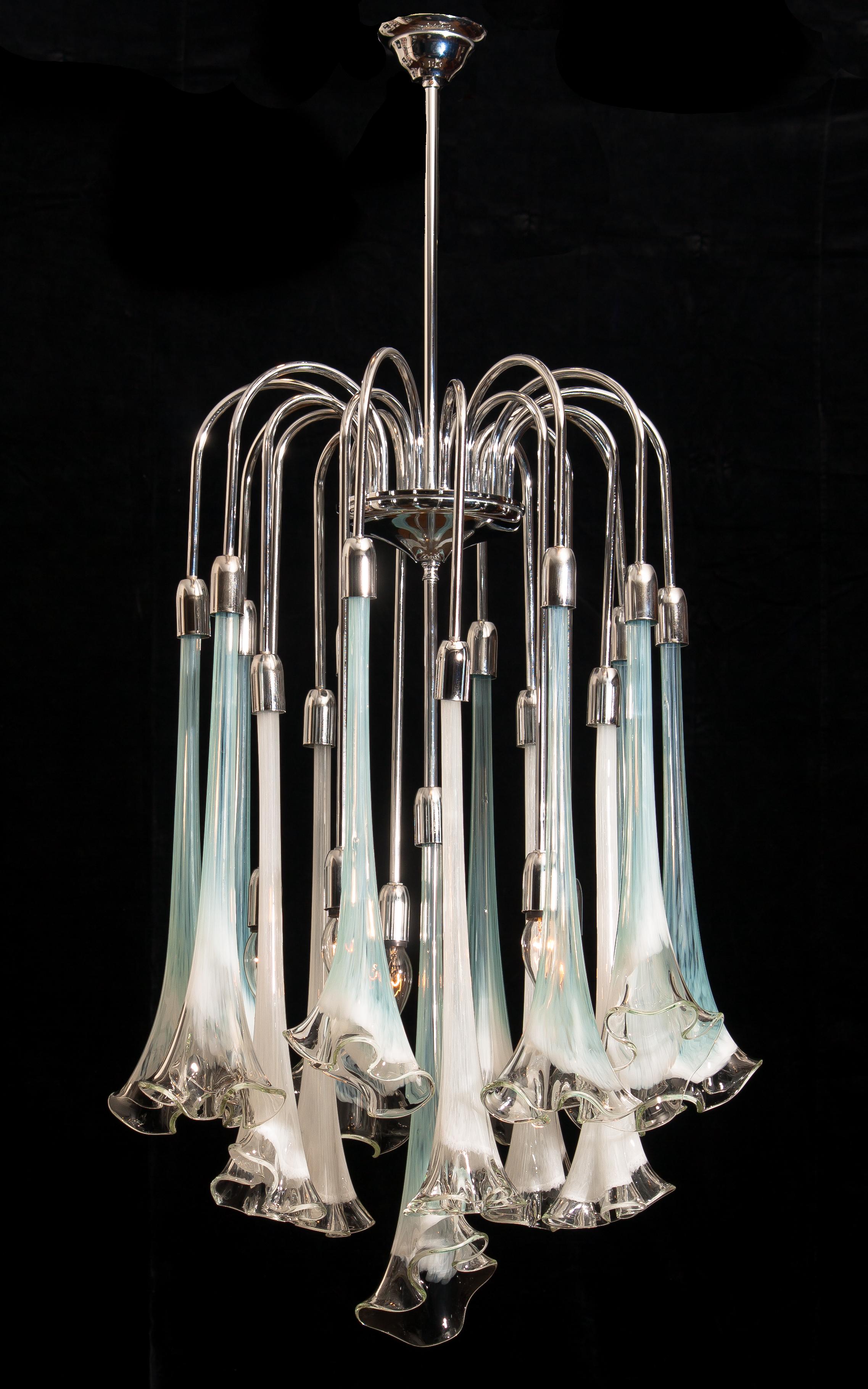 Extremely beautiful and rare Mazzega chandelier filled with Murano art glass.
The sixteen large white and turquoise glass flowers are all in excellent condition.
Also, the chrome fixture is perfect. Technically 100%.
The chandelier has five E14 /