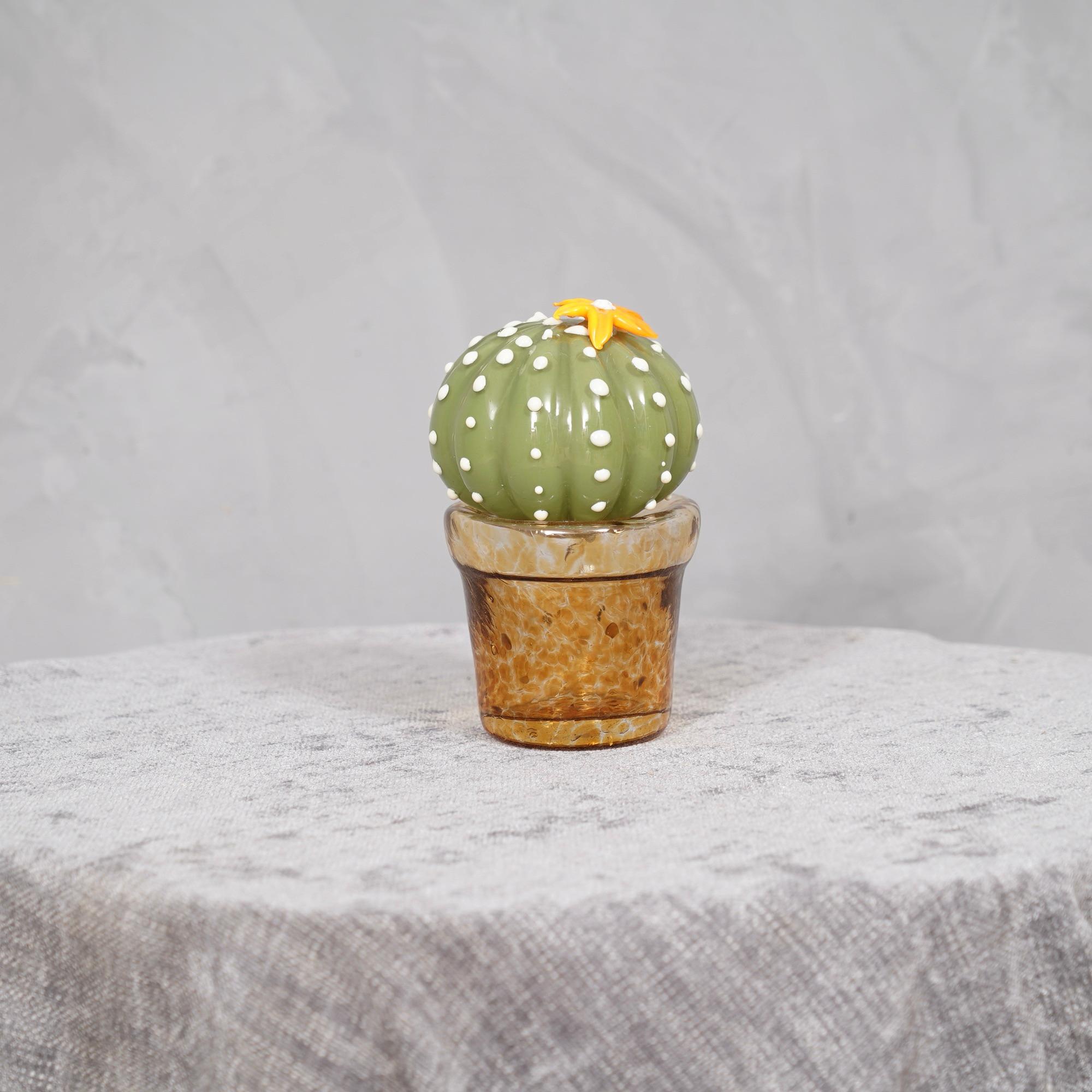 Design italiano, questo cactus è un'icona di moda dello stile italiano, di colore verde con un bellissimo vaso di vetro ambrato al di sotto. I forni di Murano creano un indiscutibile design senza tempo, semplice ma elegante allo stesso tempo. La