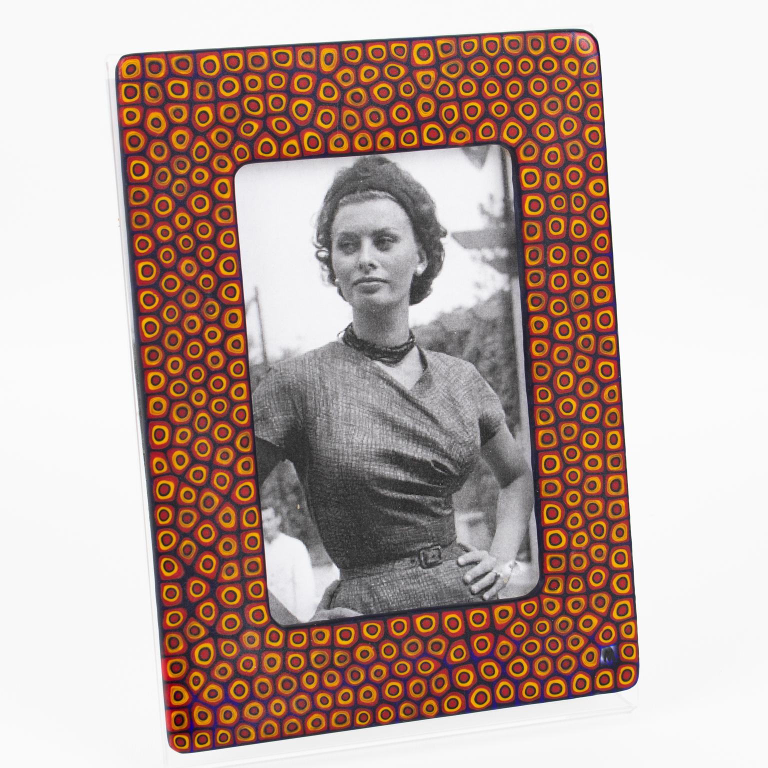 This superb Murano art glass picture frame was hand-crafted in Italy circa 1990. Murano mosaic Murrine plaques adorn the picture view of the frame, which features an L-shaped Plexiglass framing. The Murrine glass panels are matte and come in red,