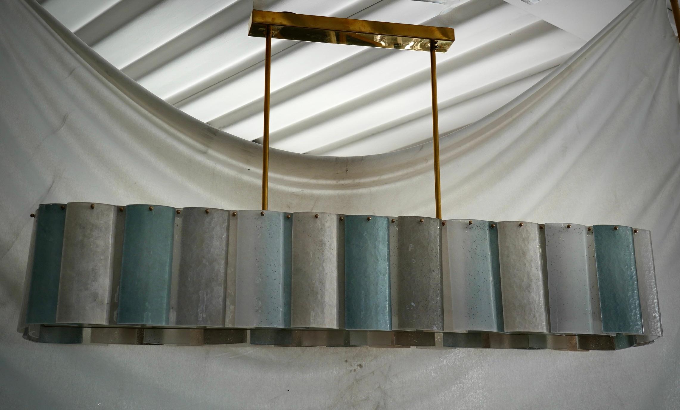 Murano chandelier with an elongated design, featuring a brass frame and uniquely colored glass. The Murano furnaces create a timeless and distinctive design, simple yet elegant.

All Murano glass with a brass frame. The glass is treated with a
