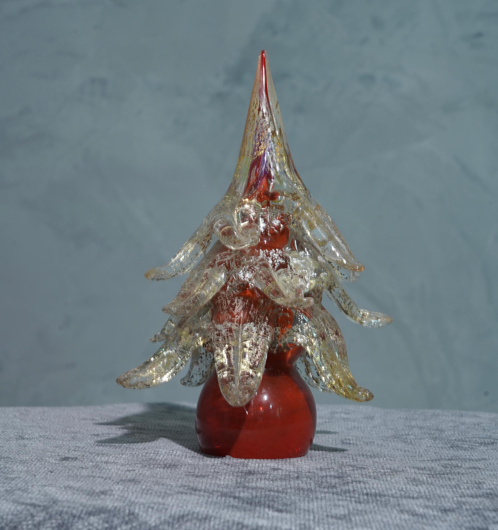 Very particular sculpture of Tree in Murano glass, stylized and linear like the art of glass in Venice commands.

The sculpture represents a stylized Christmas tree, with a red stem and large transparent leaves with specks of gold and white. You can