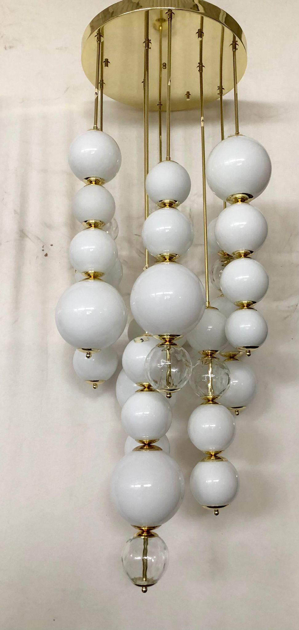 Thirty-five beautiful white spheres positioned in sequence in nine series, beautiful and particular design for this Murano glass chandelier.

The chandelier is composed of a high galvanized brass disc, from which 9 rows of Murano glass spheres hang,