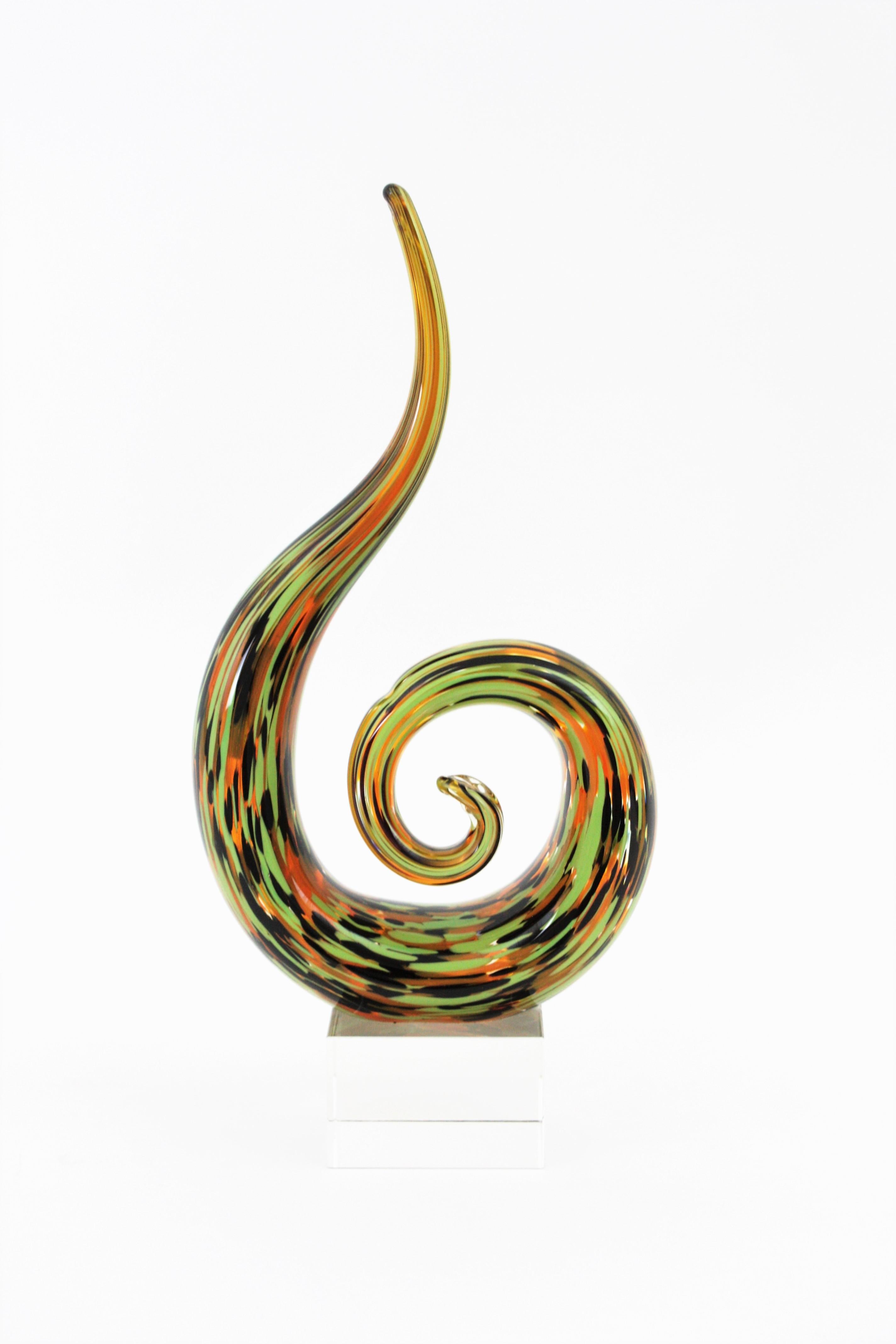 Beautiful abstract Murano blown glass sculpture. Artist unknown. Italy, 1960s
This art glass paperweight sculpture has an eye-catching design with spiral shape standing on a clear glass cube pedestal. It is made of clear glass with murrine