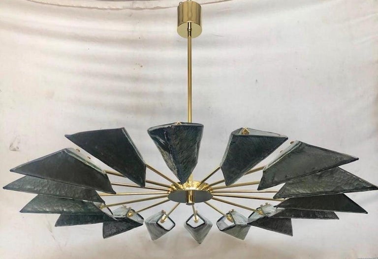 Simple and linear but there is all the style of Murano in this splendid chandelier with a beautiful green / blue color.

The chandelier has a structure made of polished brass tubes, to which particular Murano glass tiles have been inserted; note