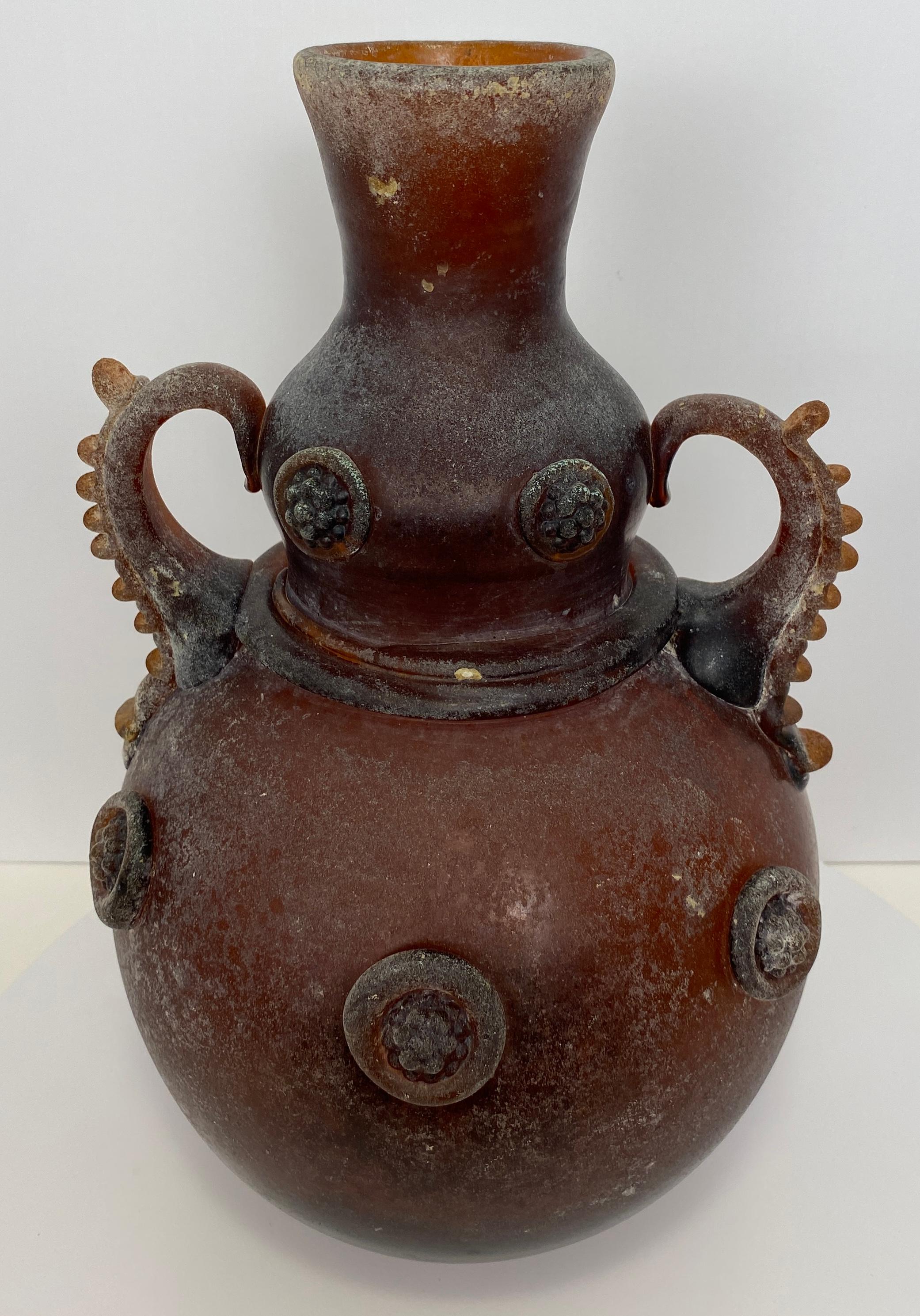 Murano Art Glass Vase with Handles, Roman Revival Style

A striking hand-blown Murano art glass vase featuring richly sculpted twin handles and applied circular prunts in relief. The deep amber-brown tone and textured surface give the piece an aged,
