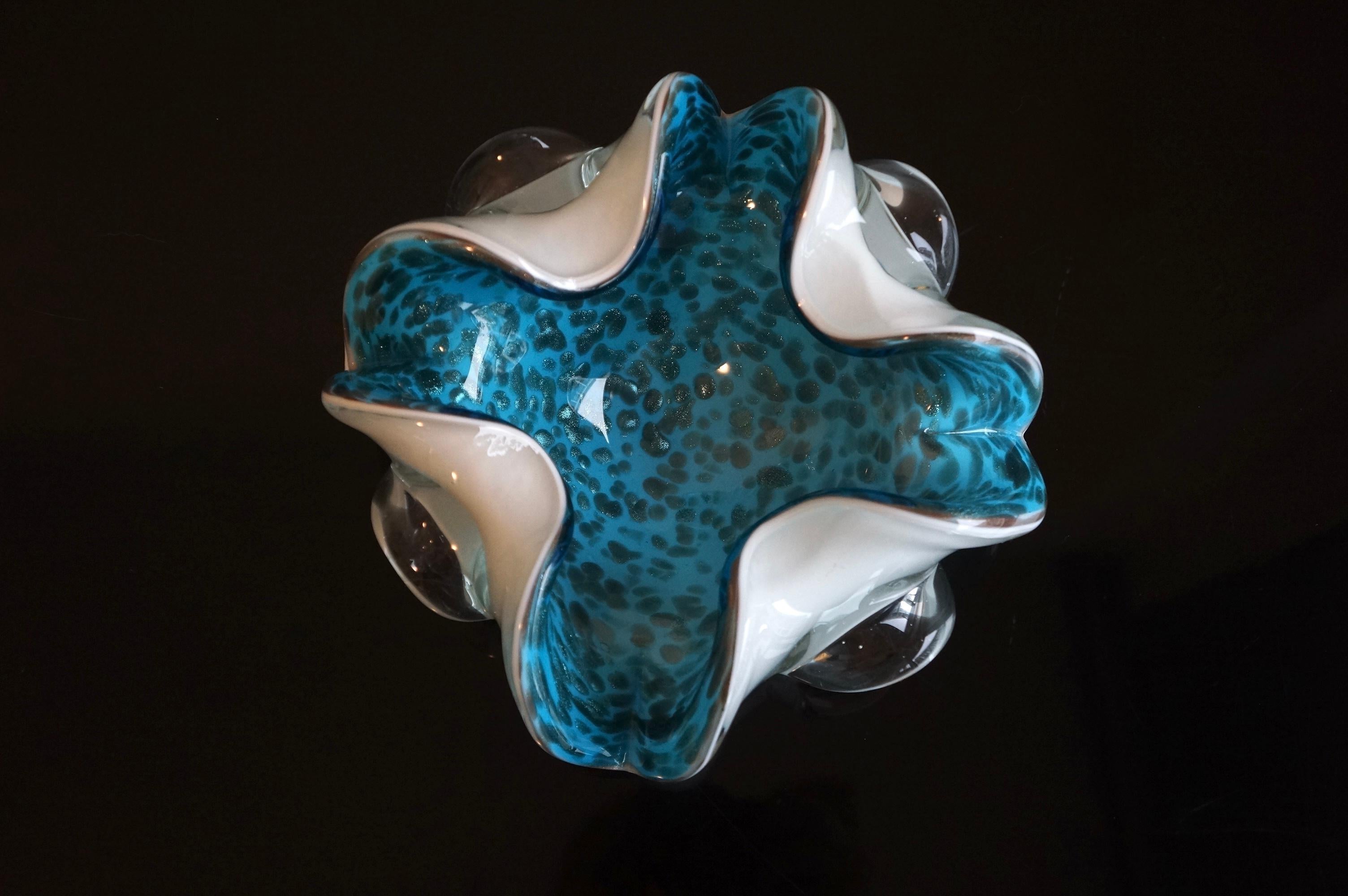 Splendido piatto decorativo in bianco, blu e oro screziato. Questa ciotola è realizzata con una base bianca, vetro artistico stratificato blu con puntini di avventurina in tonalità oro. L'esterno è in vetro bianco opalino, mentre l'interno è