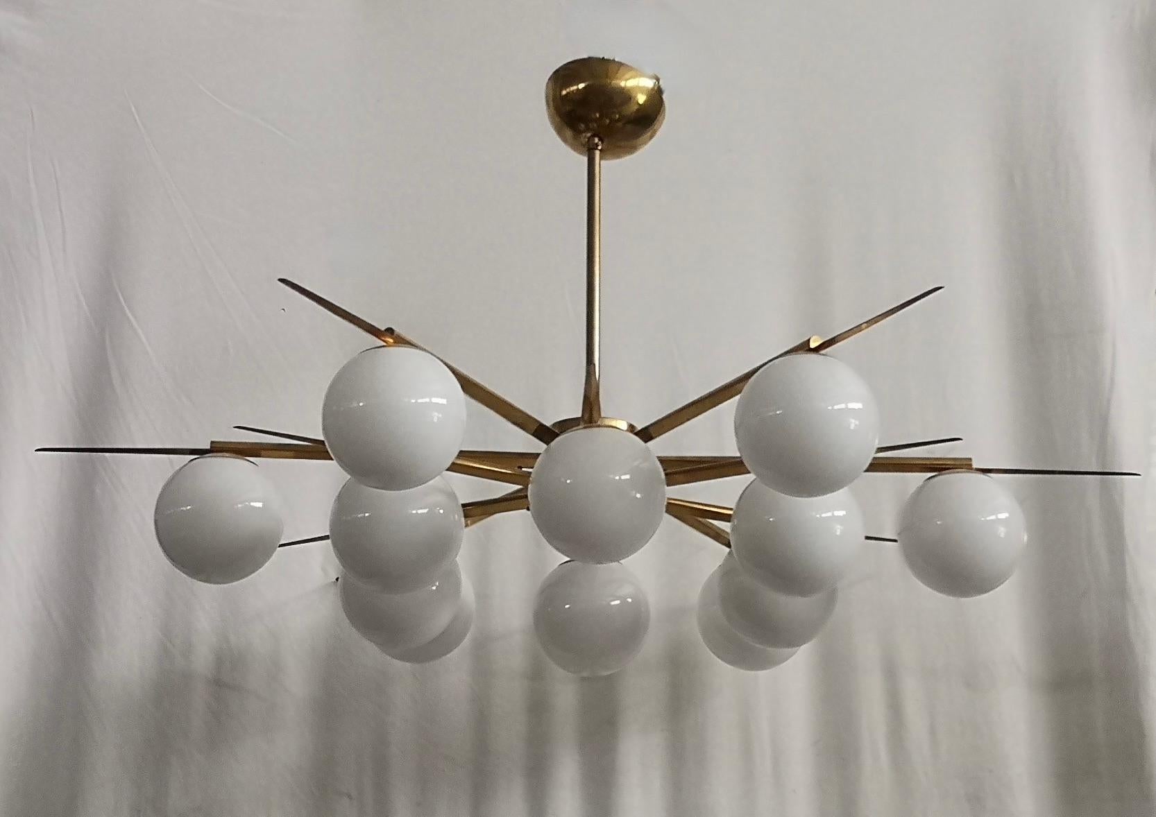 Linear and precious sputnik chandelier with a very particular design also due to the choice of materials such as brass and white Murano glass.

The chandelier is composed of a central brass stem from which 12 brass swords unravel to which Murano