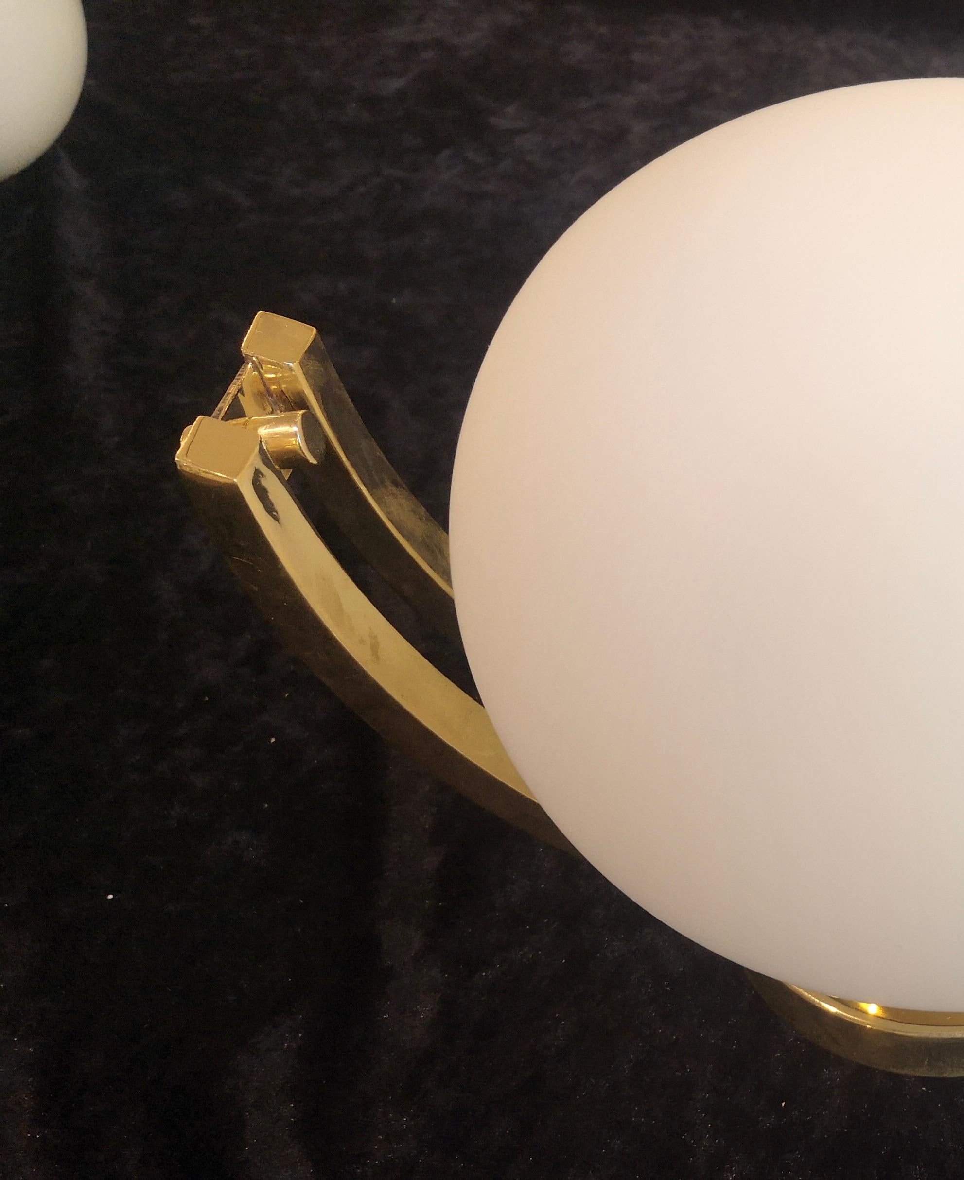 Very classic Murano glass wall light, rich and elegant design, its taste is delicate.

The wall lamp is composed of a brass structure formed by two curved arms that wrap a white glass sphere. Its polished brass frame makes it very rich with a
