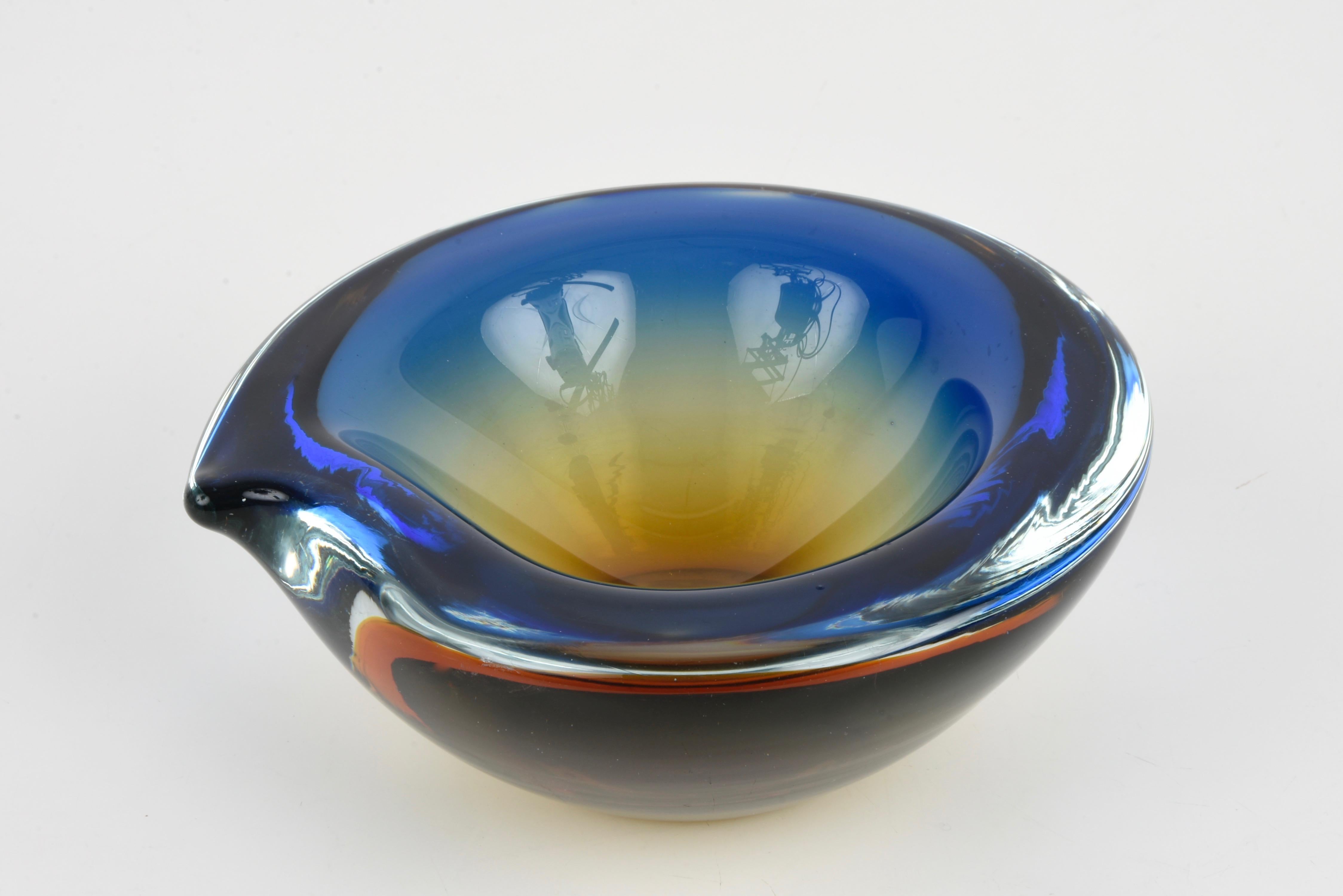 Magnificent bowl or ashtray in Murano glass blue with amber shades. This fantastic item was produced in Italy in the 1960s. 
This wonderful piece is a perfect blend of sinuous and sexy lines and colors of Murano glass thanks to the mastery of the