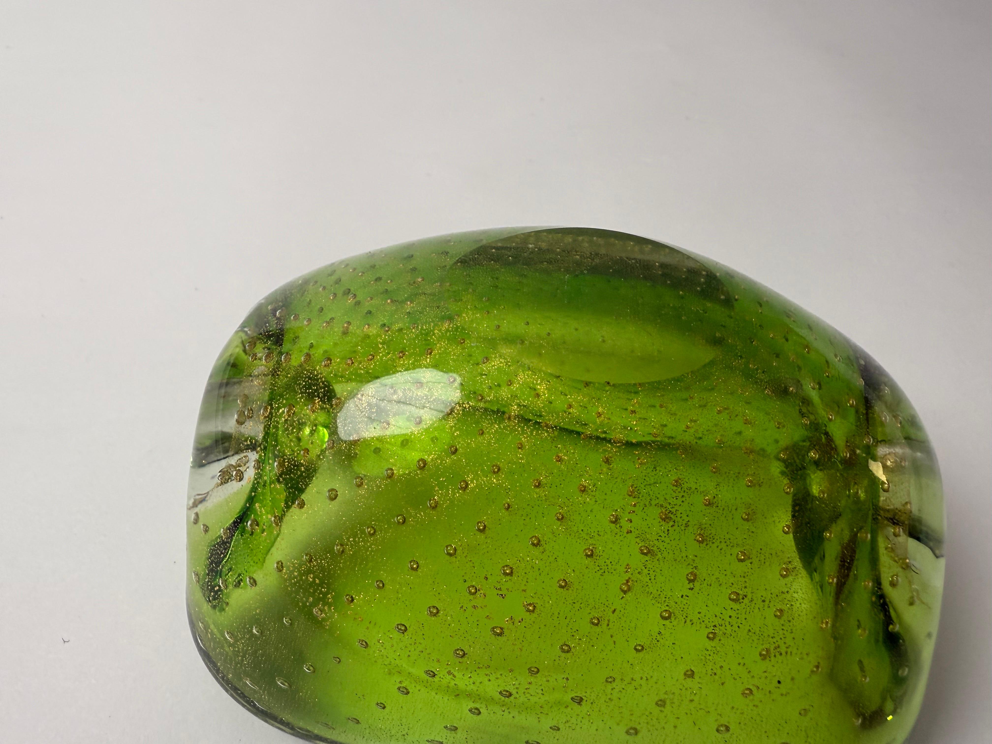 Este cenicero verde de Greeny Smith es una auténtica belleza, con diminutas burbujas de aire que se arremolinan como un remolino y el más fino polvo de oro. Esta pieza única se fabricó en la bella ciudad de Murano, Italia. Su combinación de colores
