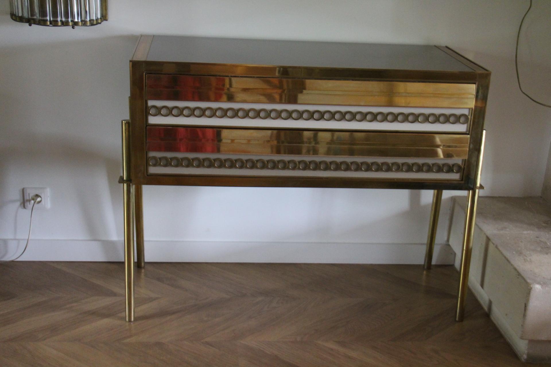 This is an exquisite Italian fine design one of a kind cabinet . It features golden polished brass trims, legs and decorative circle motives brass and ivory white and grey color Murano glass . It opens thanks to 2 drawers that slip very smoothly.