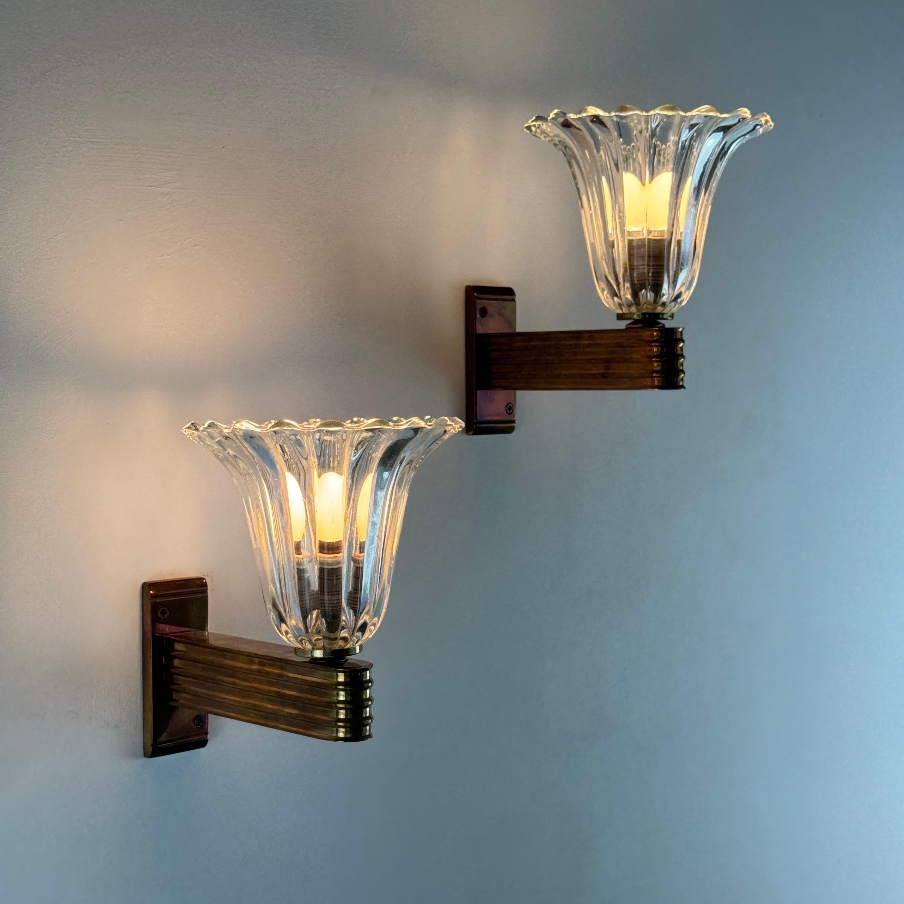 Encantador par de apliques de pared atribuidos a Ercole Barovier para Barovier & Toso, de la década de 1940, magistralmente elaborados en cristal de Murano soplado a mano con difusores en forma de campánula.

Las pantallas de cristal transparente y