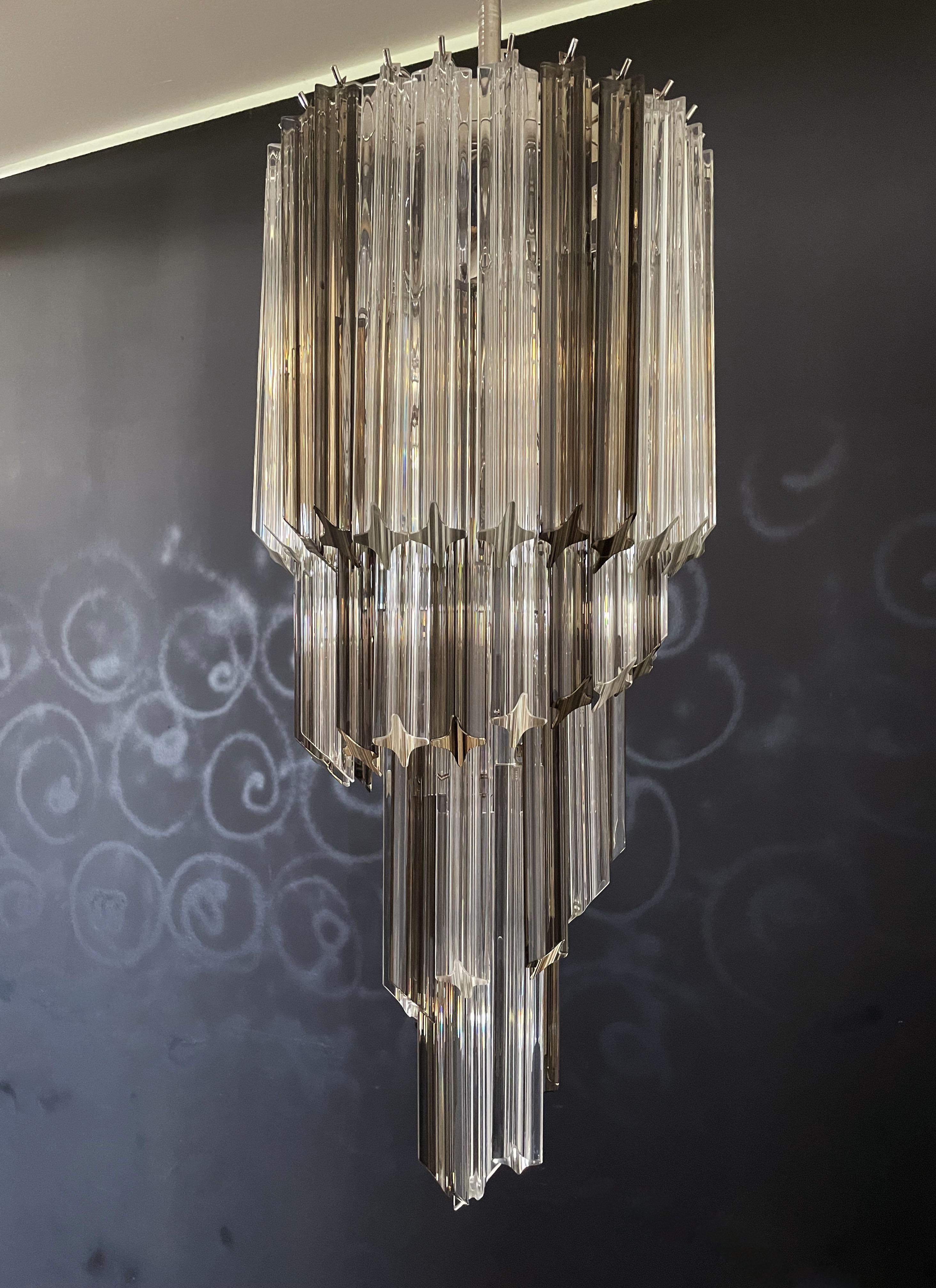 Fantastique et grand lustre de Murano composé de 54 prismes en cristal de Murano (quadriedri) dans une structure en métal chromé. La forme de ce lustre est en spirale. Les verres sont de deux couleurs différentes, 24 fumées et 30