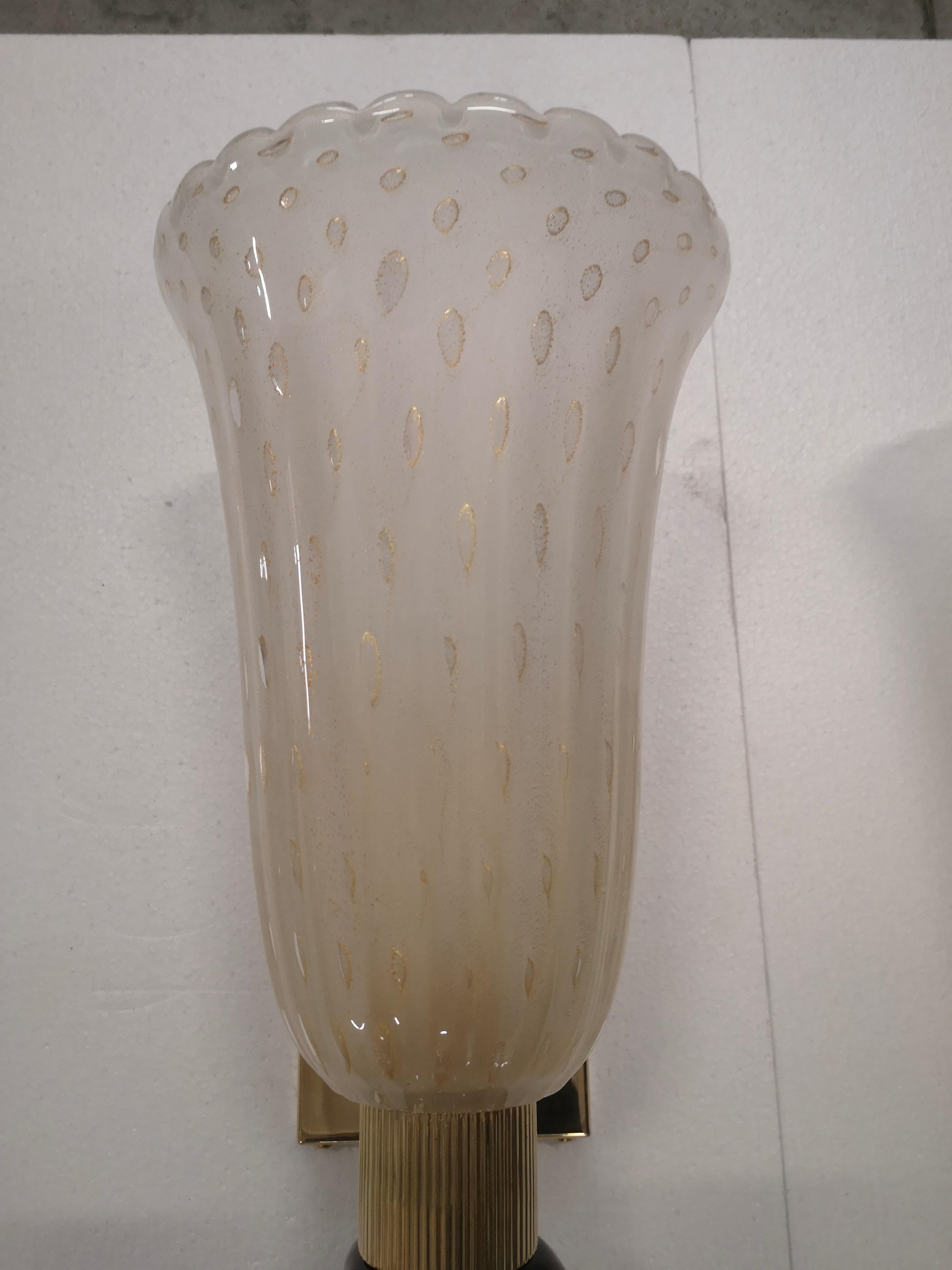 Refined and delicate design for this pair of wall light with black and cream color Murano glass.

The pair of wall light has a brass structure, on which a beautiful cream-colored Murano glass cup has been mounted on the upper part, which contains