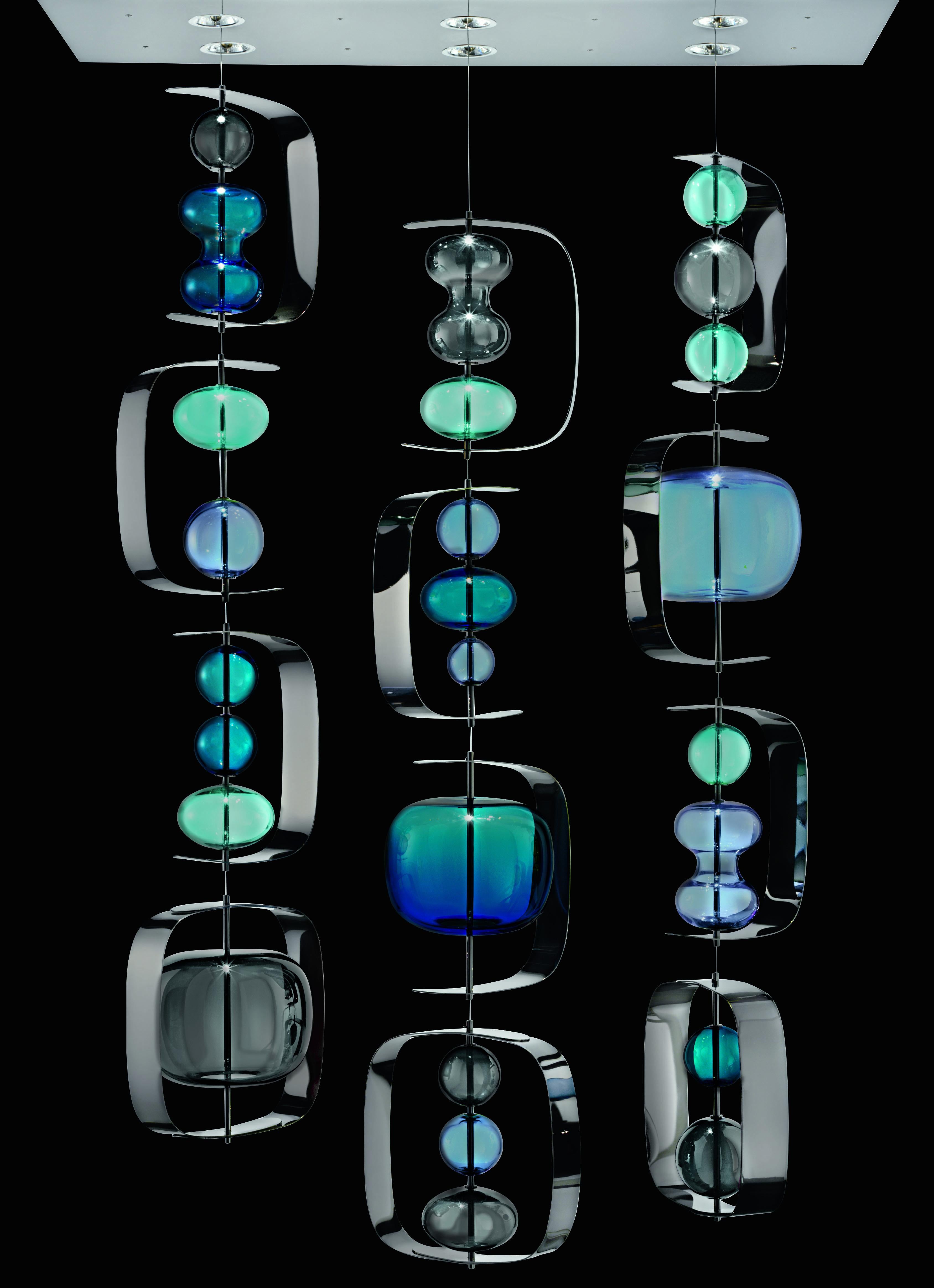 Suspended metal frames from where blown Venetian crystal bubbles float in the air. Available in two coloured palettes or in white and transparent version. Three different compositions (one, three or four steel cables), and two heights.
