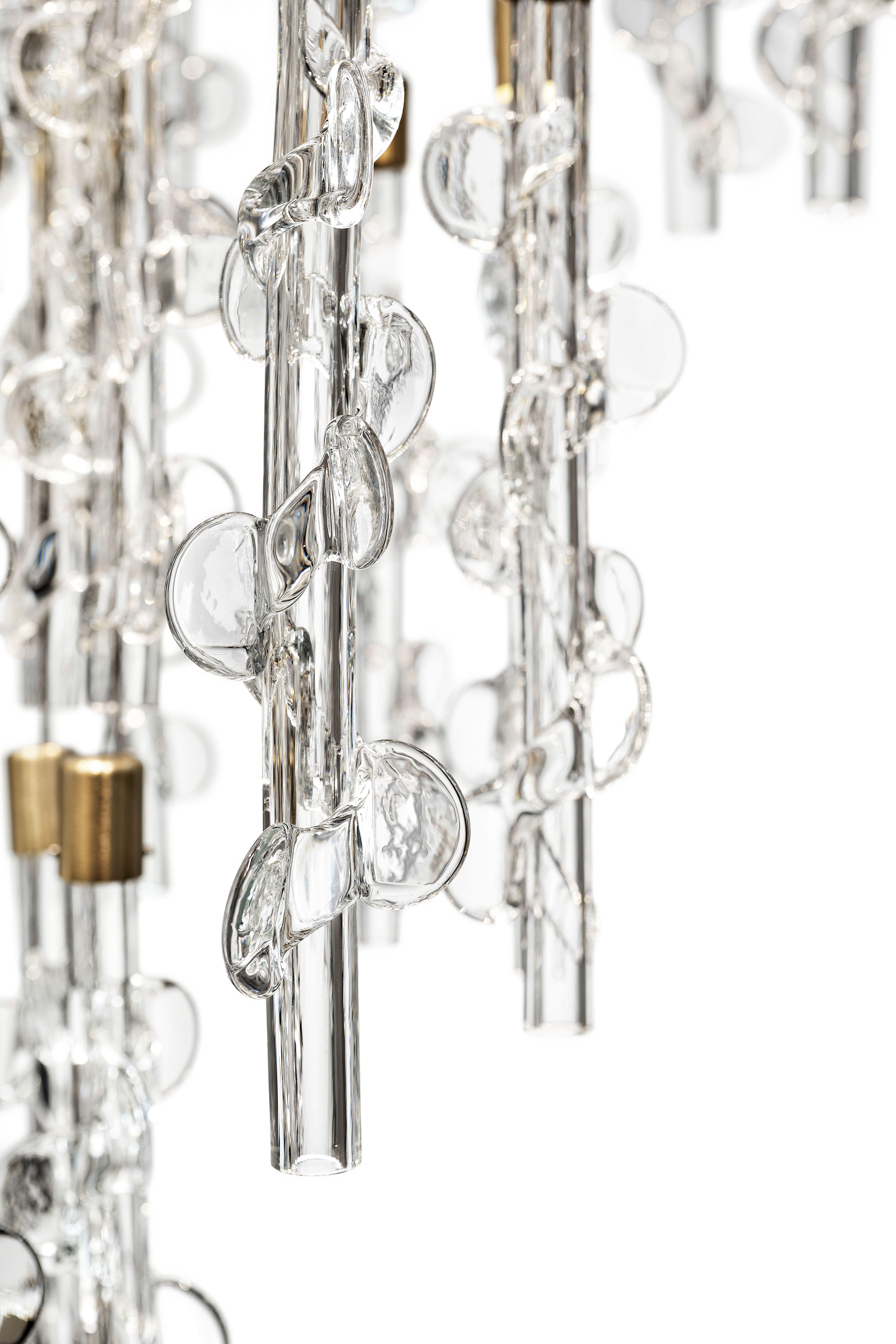 Al centro della scena, l'intreccio di canne luminose, avvolte da foglie di piante rampicanti, interamente realizzate in cristallo veneziano. Il mondo botanico ritorna come fonte di ispirazione, in linea con l'eredità di Murano. I disegni provenienti