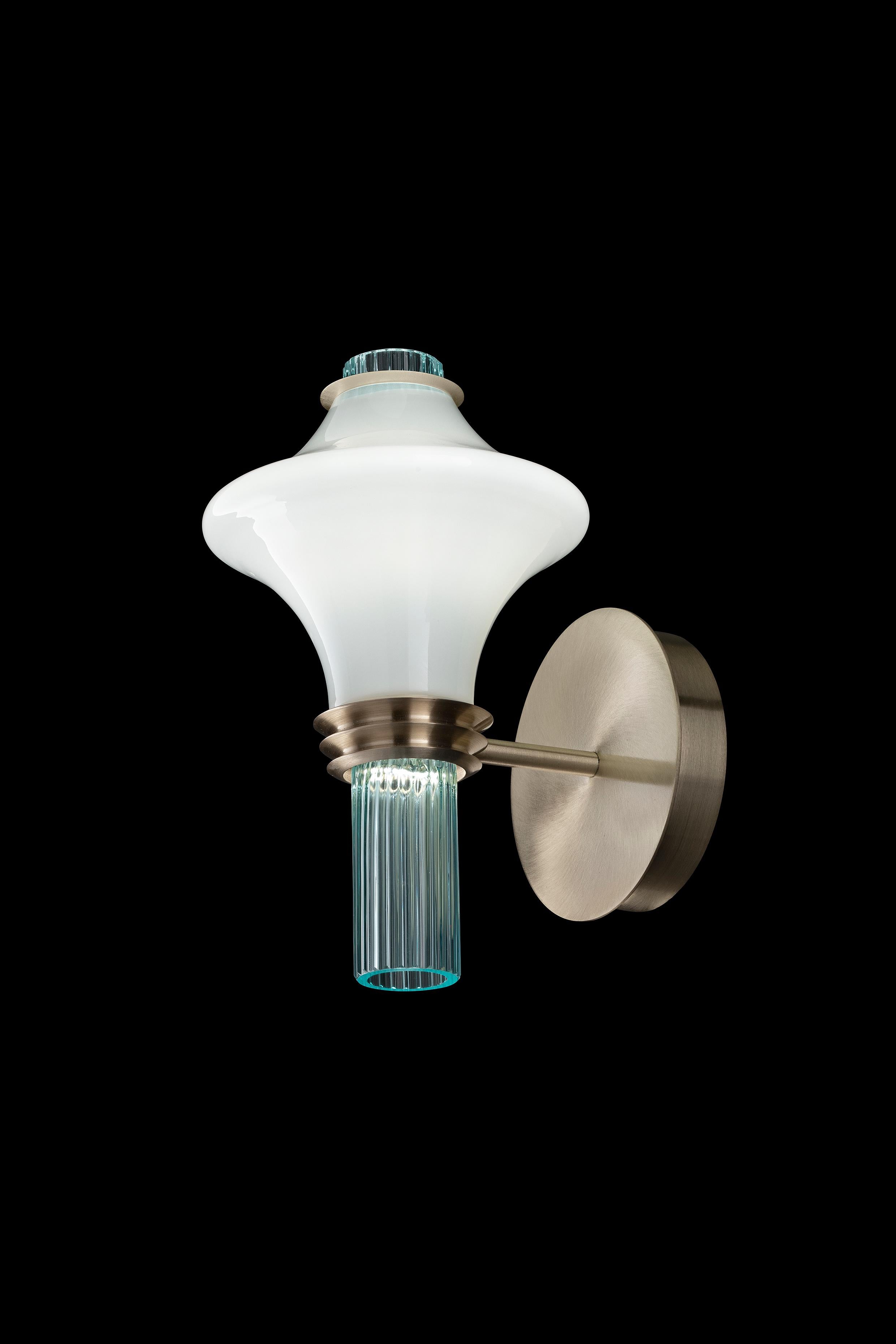 Metrópolis es una colección que evoca con fuerza las formas clasicistas, simétricas y plásticas del Art Déco, modeladas por un ritmo armonioso y fluido. La fuente de luz está oculta dentro de las copas de cristal opalino, abrazadas en los dos