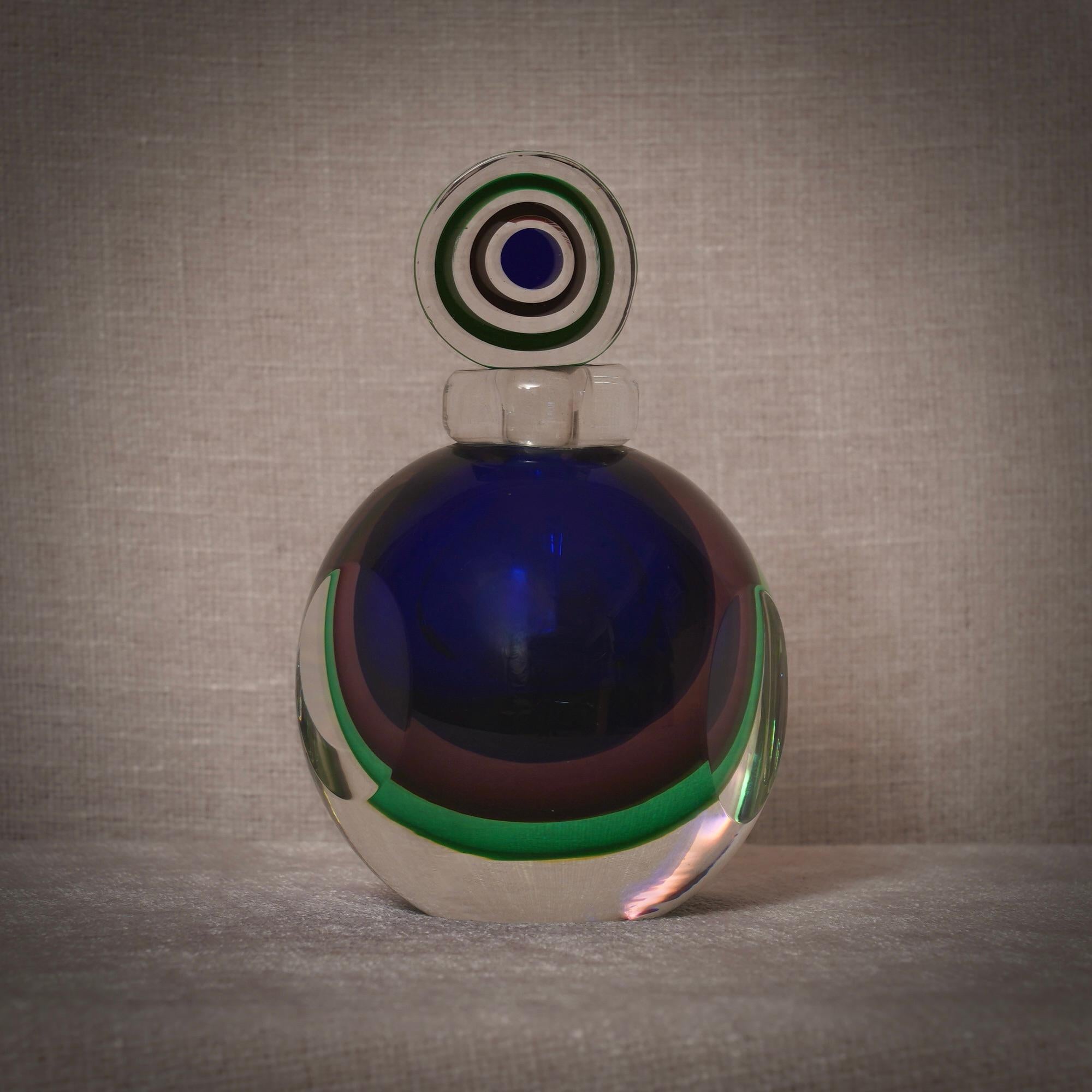 A perfume bottle with internal decorations in various shades of blue, green, and transparent. A sculpture of the highest quality, one of a kind in Murano.

A classic of Murano glassworks, the perfume bottle remains a status symbol in Murano. This