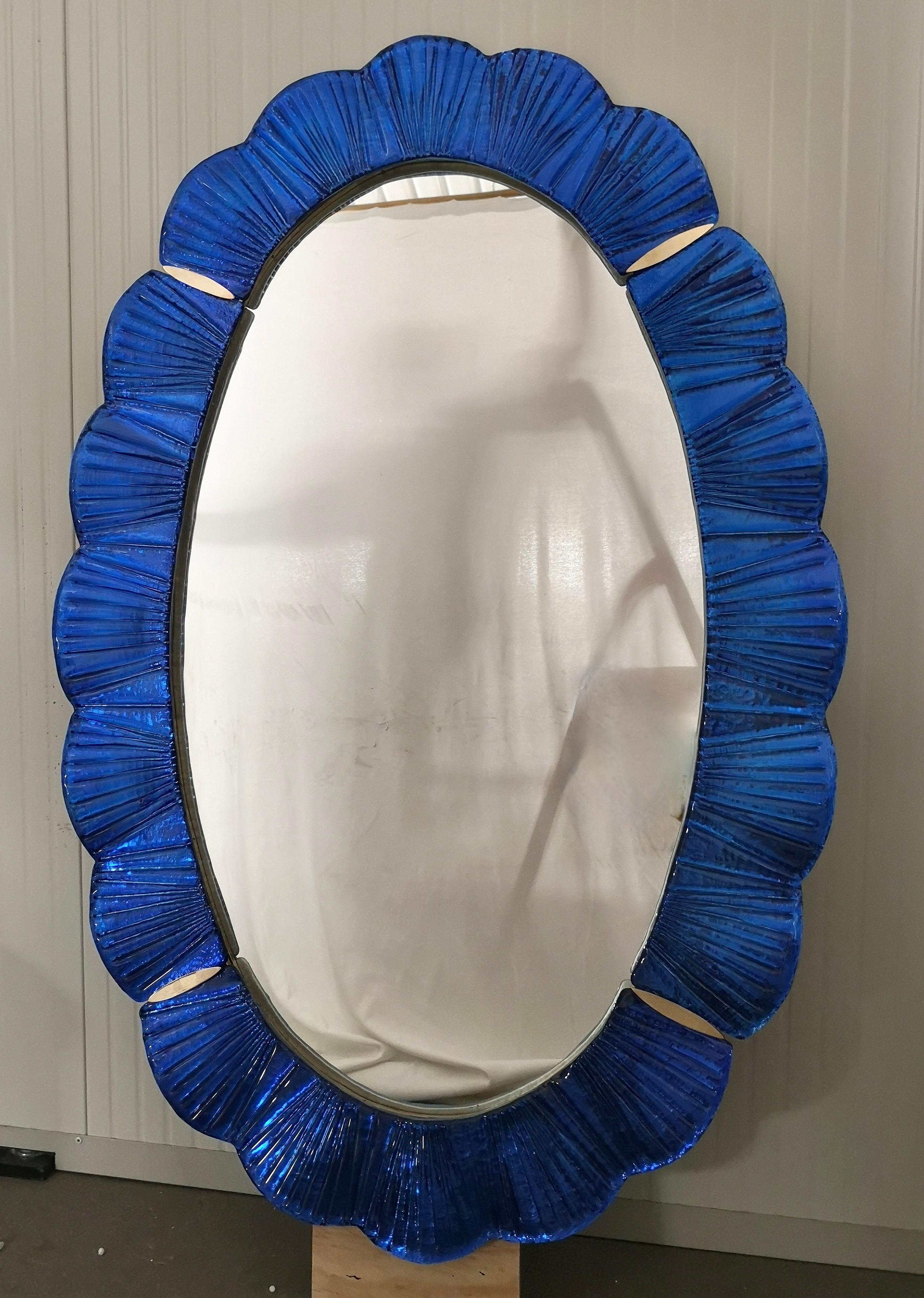 Atemberaubender Spiegel aus leuchtend blauem Murano-Glas, Venedig. Ein Spiegel, der allein Ihr Zuhause einrichtet.

Der Spiegel hat eine Rückwand aus Holz, auf der vier Murano-Glasscheiben montiert sind, die wie auf dem Foto ein Oval bilden. Der